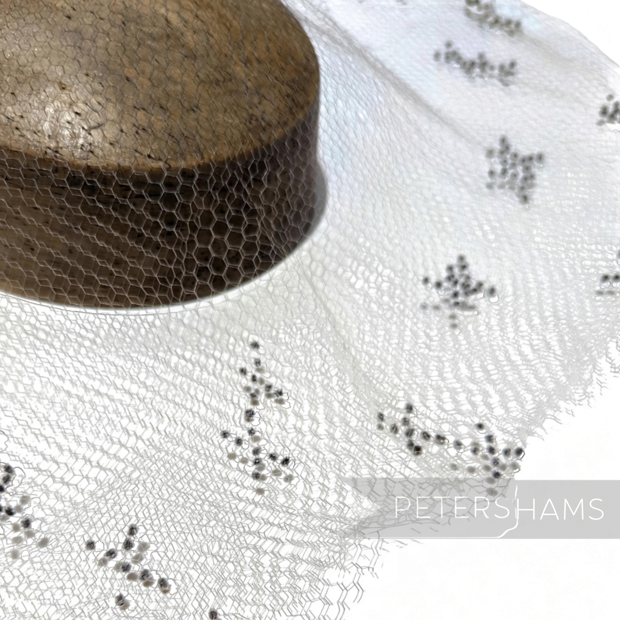 Petershams Millinery Supplies vintage honeycomb veiling round with black X-shaped embroidery on a wooden hat block
