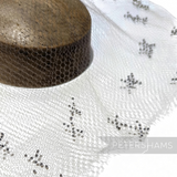 Petershams Millinery Supplies vintage honeycomb veiling round with black X-shaped embroidery on a wooden hat block