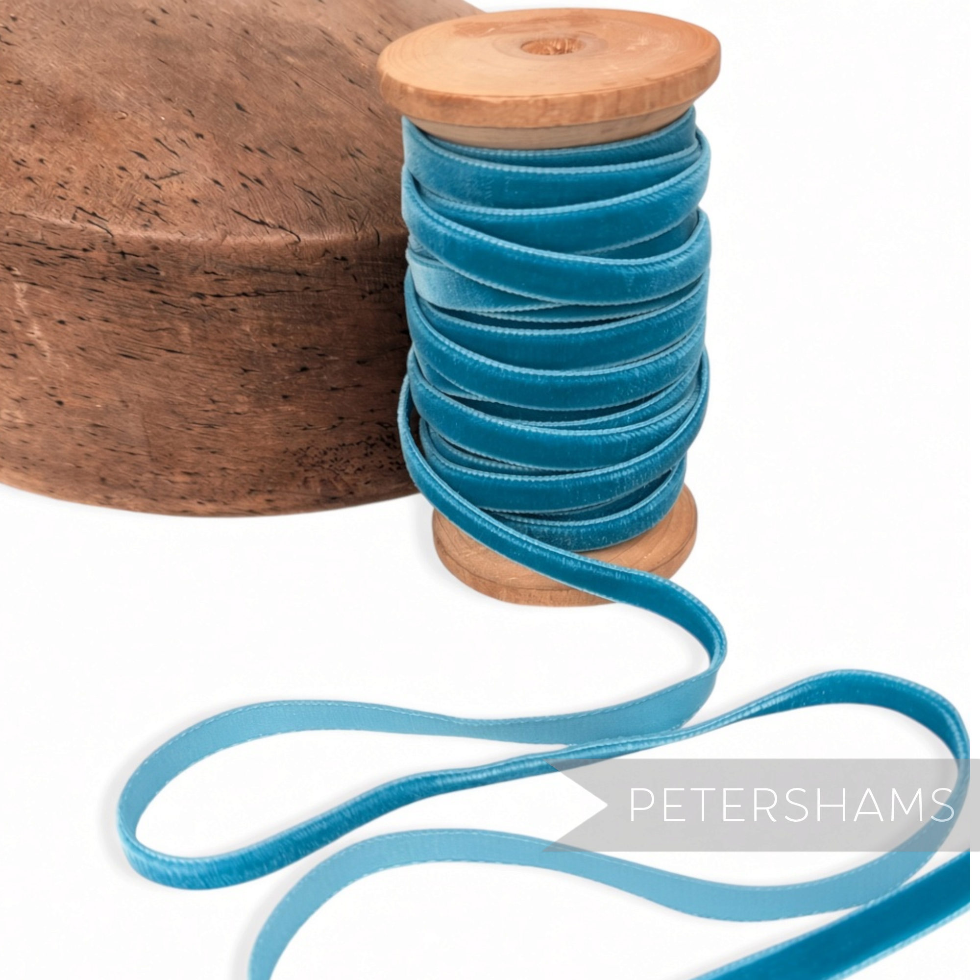 Petershams Millinery Supplies 7mm vintage blue velvet ribbon on a wooden spool next to a wooden millinery block