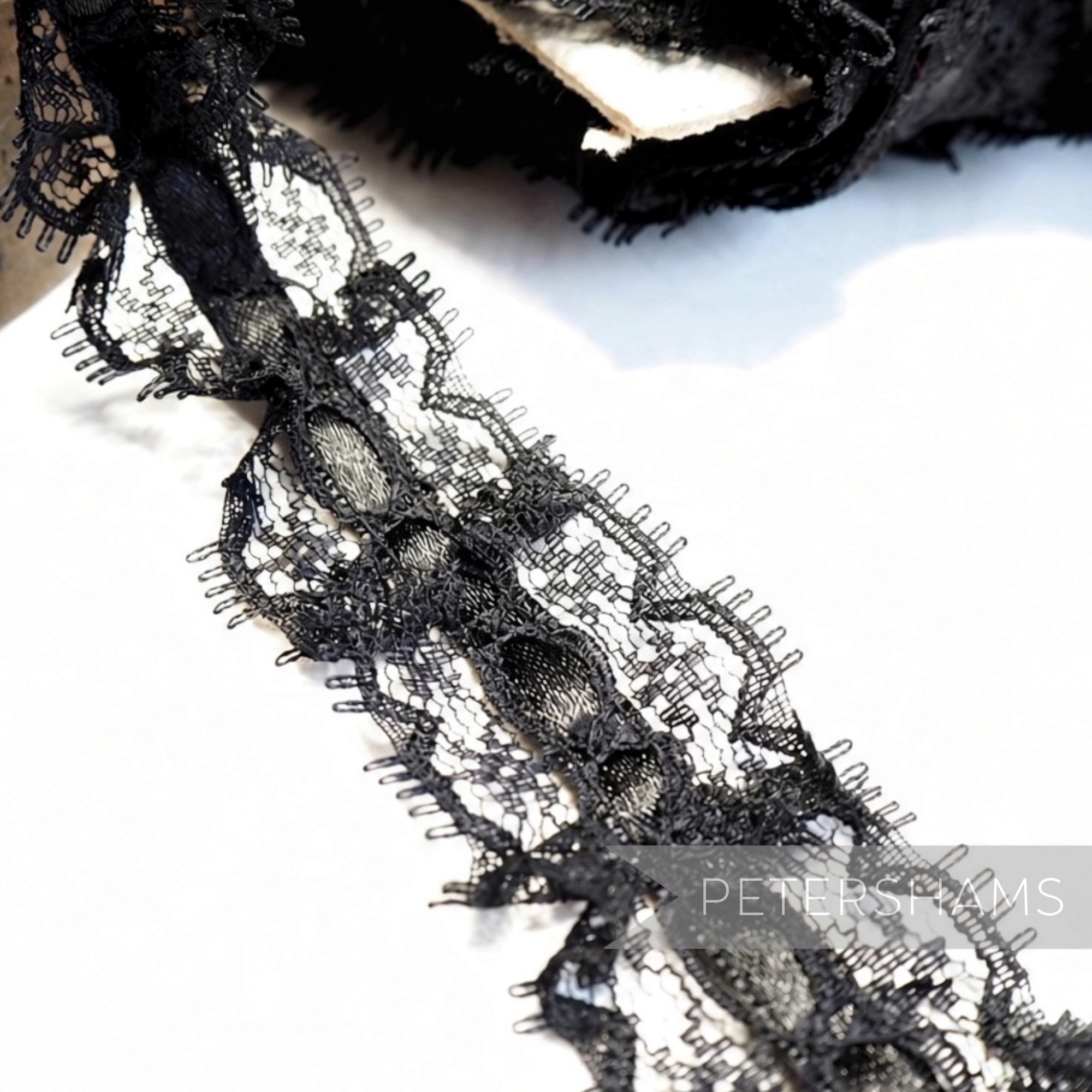 Petershams Millinery Supplies 25mm black frilly lace trim with a central satin ribbon detail