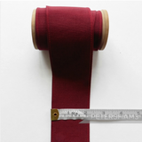 Petershams Millinery Supplies 53mm wide deep red ribbed belting ribbon on a wooden spool with a measuring tape.