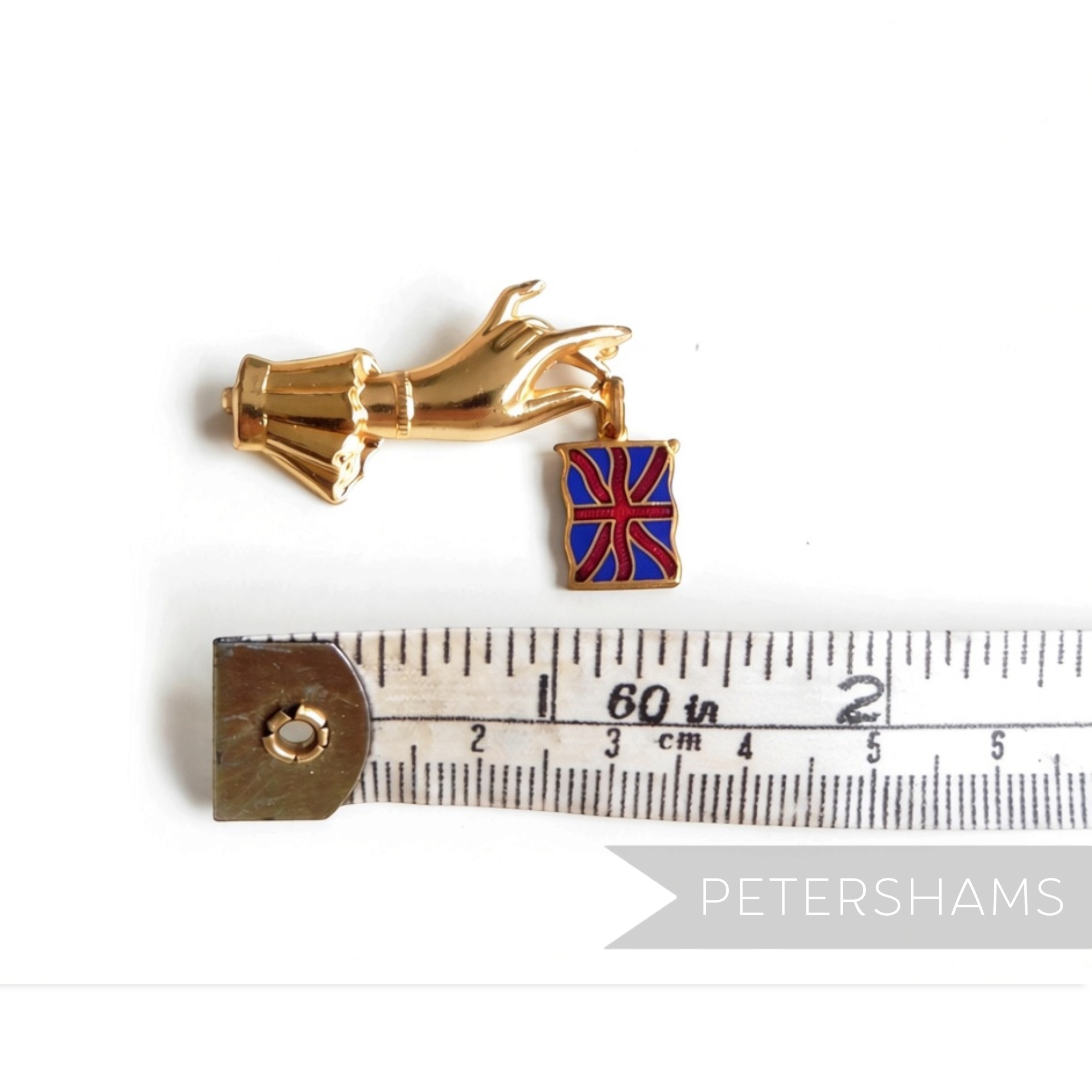 Petershams Millinery Supplies vintage 1940s gold-tone hand brooch dangling a Union Jack flag on a measuring tape
