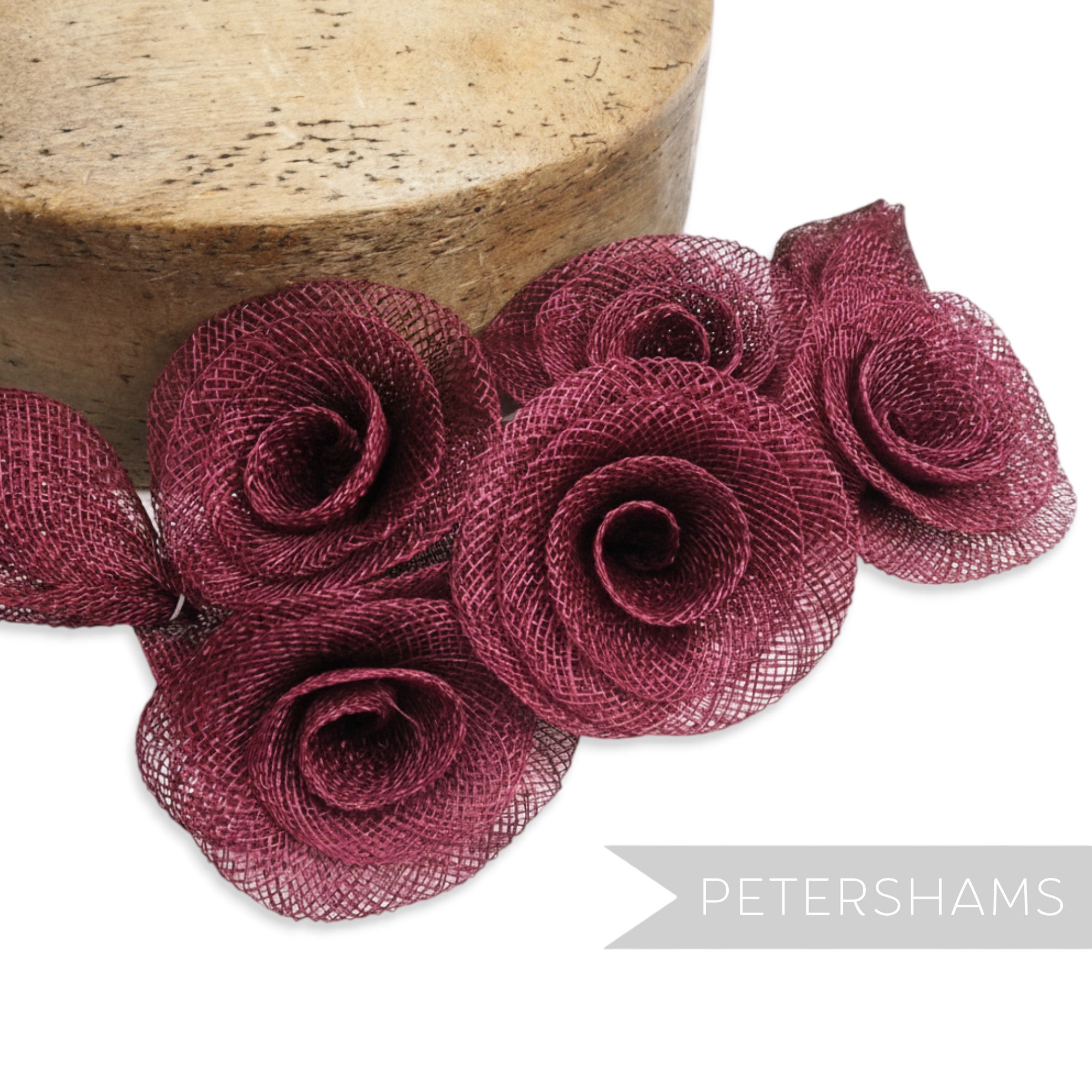 Petershams Millinery Supplies burgundy sinamay flower and leaf hat mount. Five rose-shaped flowers with a flat backing.