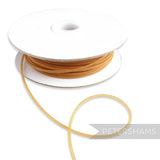 Petershams Millinery Supplies gold tubular crin, 2.5mm wide, with a central thread for gathering. Ideal for headbands and graphic shapes.