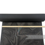 Petershams Millinery Supplies black double sided stiffened cotton buckram fabric roll with a measuring ruler on top.