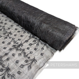 Petershams Millinery Supplies black sinamay fabric with leaf embroidery and organza backing on a roll.
