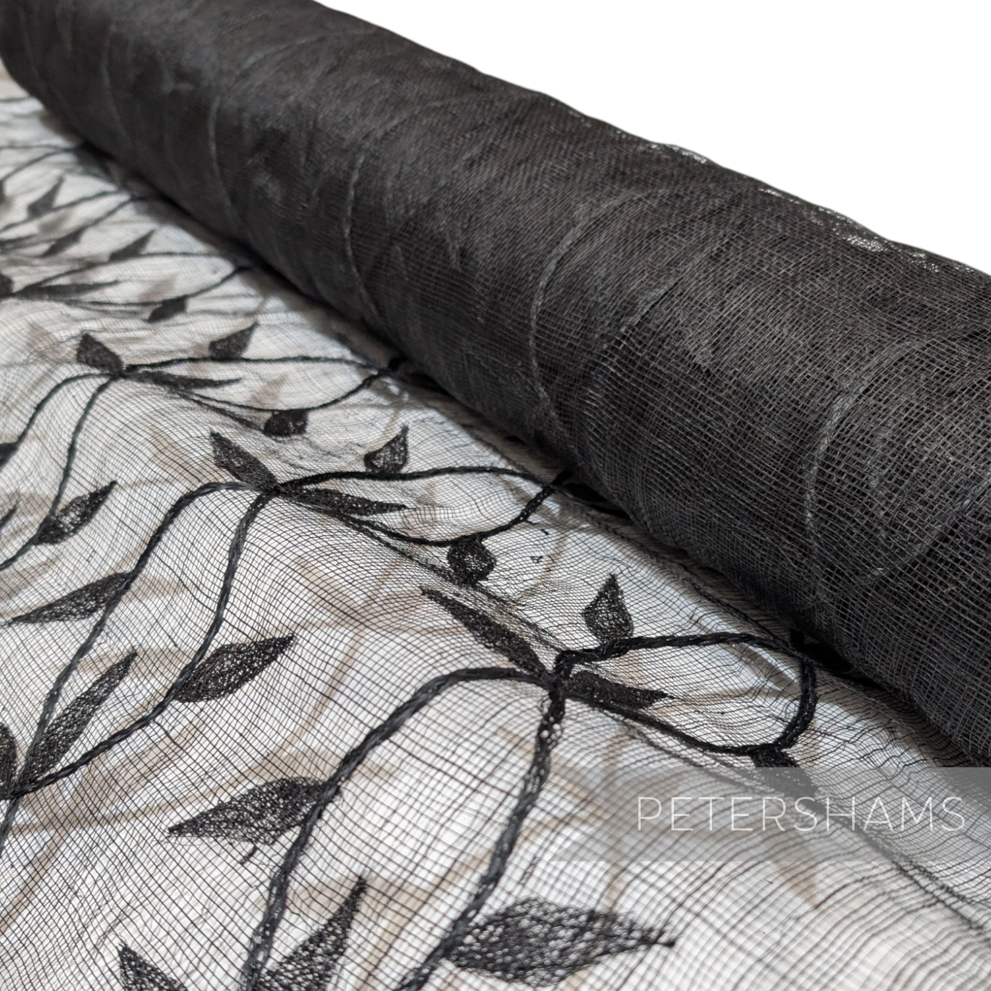 Petershams Millinery Supplies black sinamay fabric with an applique leaf vine pattern on a rolled bolt.
