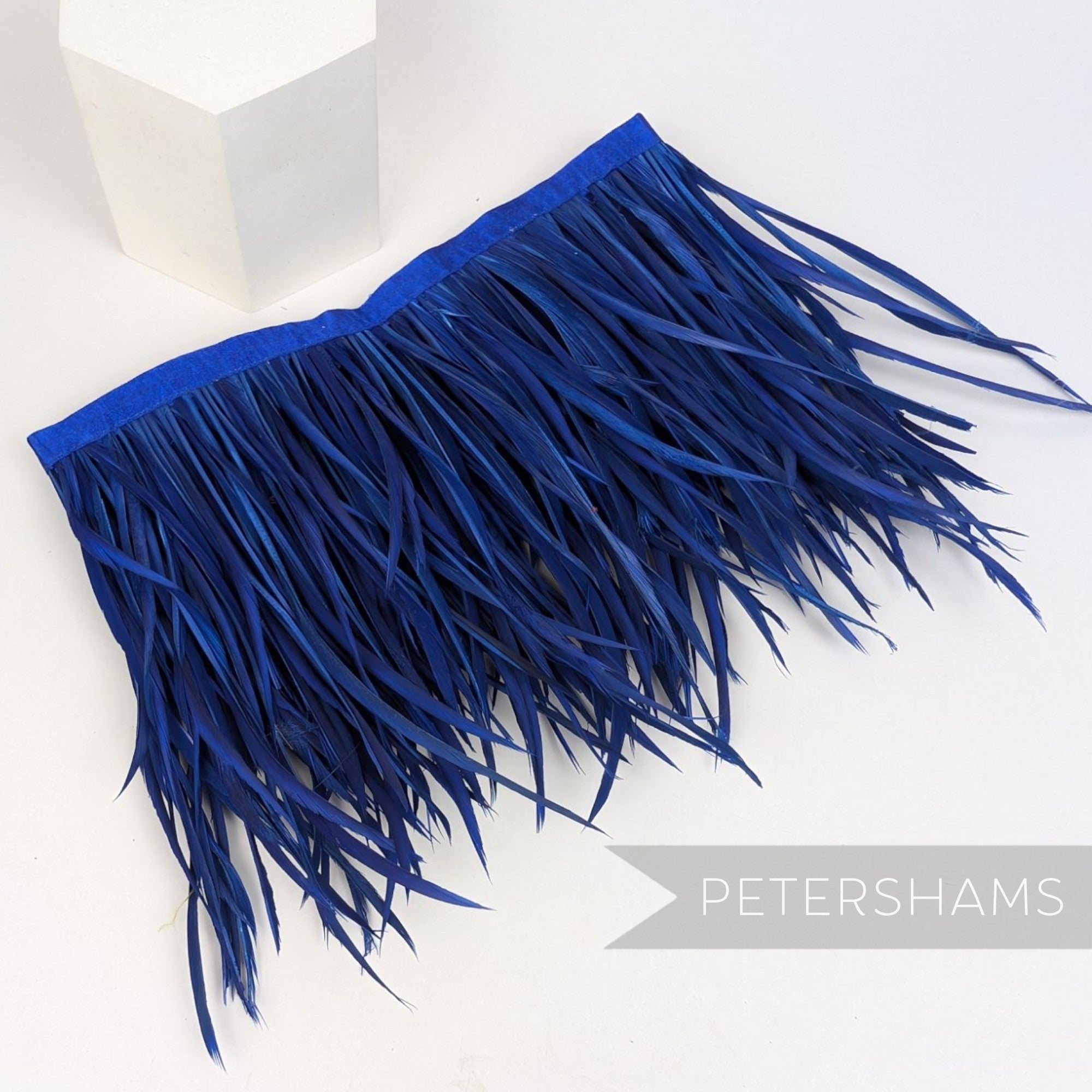 Petershams Millinery Supplies extra long royal blue goose biot feather fringe on a stitched satin ribbon binding.