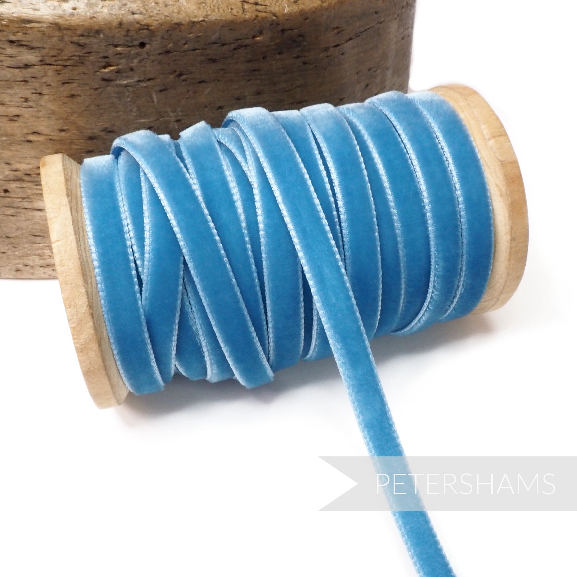 Petershams Millinery Supplies 7mm vintage blue velvet ribbon on a wooden spool for millinery and craft projects.
