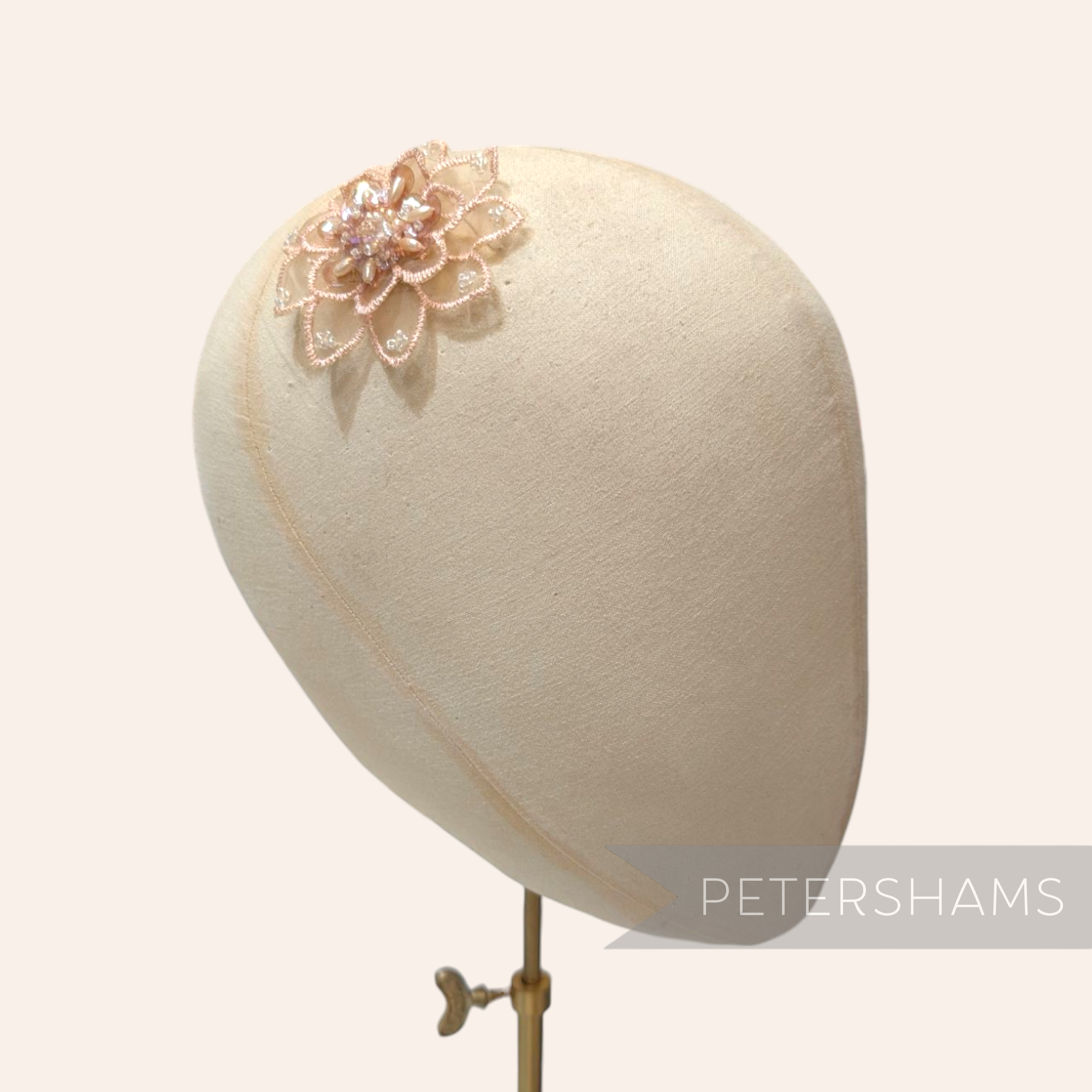 Petershams Millinery Supplies blush organza flower motif with intricate bead and sequin detailing on a mannequin head.
