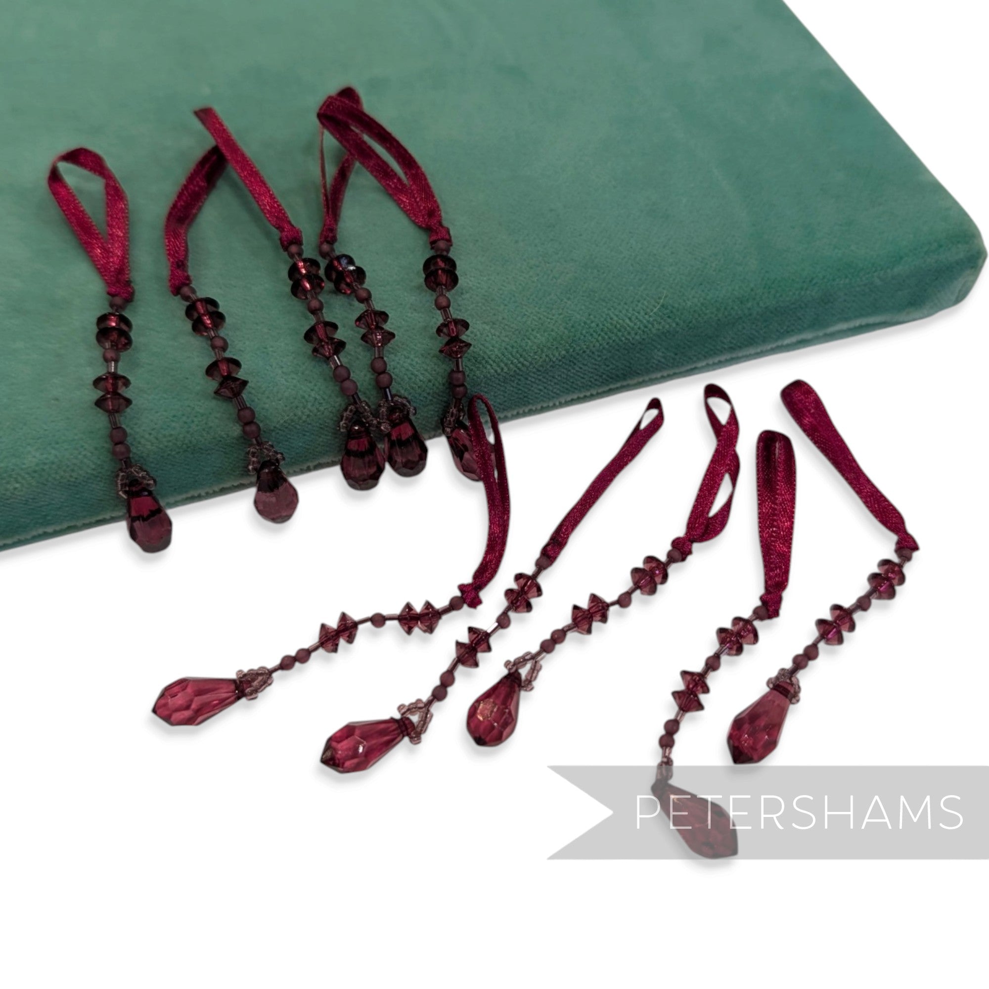 Petershams Millinery Supplies pack of 10 burgundy teardrop beaded tassels with satin hanging loops.