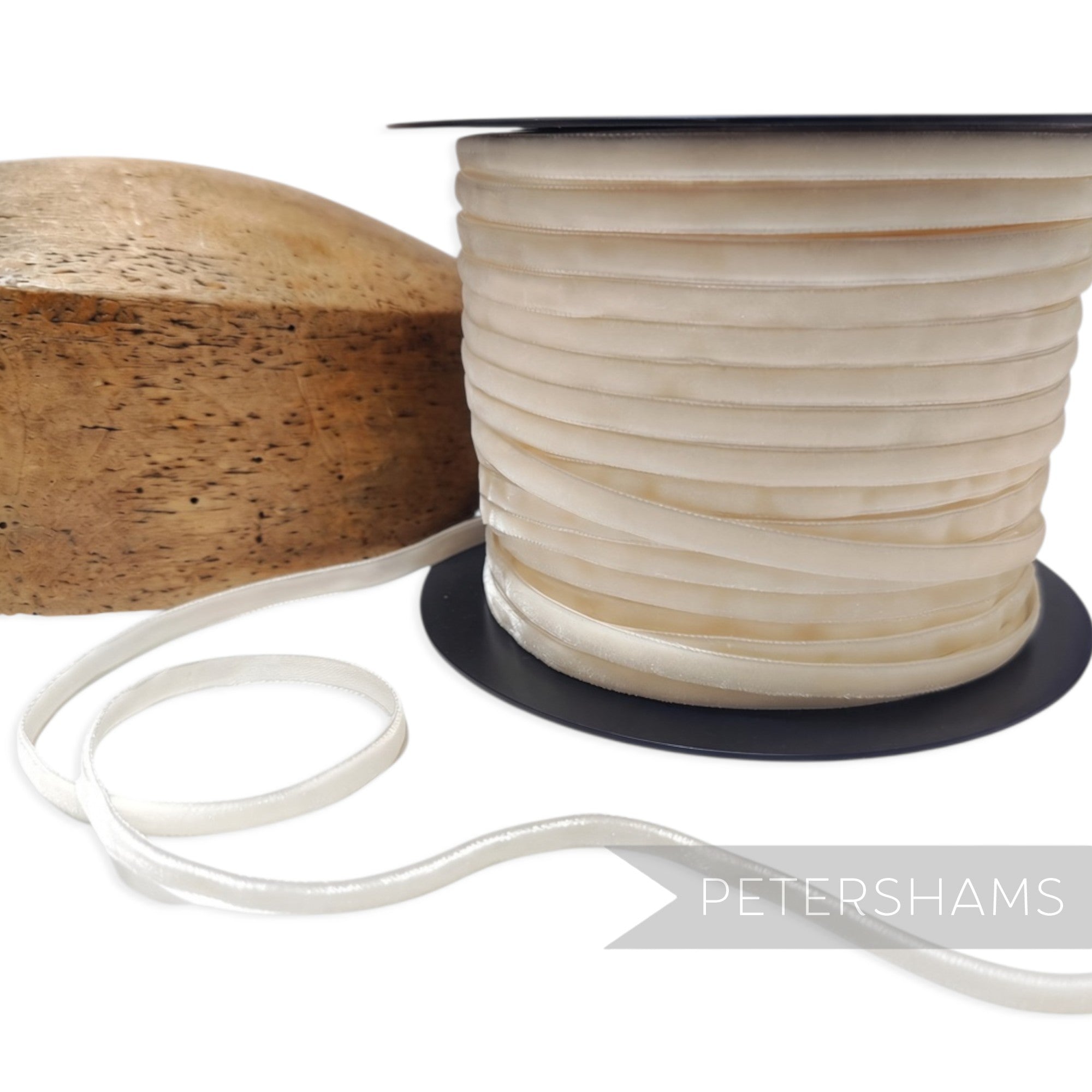 Petershams Millinery Supplies 7mm ivory French velvet ribbon on a spool next to a wooden hat block