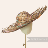 Petershams Millinery Supplies dark straw capeline with a fringed brim and colorful rope accents on a hat block.