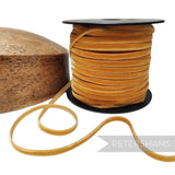 Petershams Millinery Supplies 7mm gold French velvet ribbon on a spool next to a wooden hat block