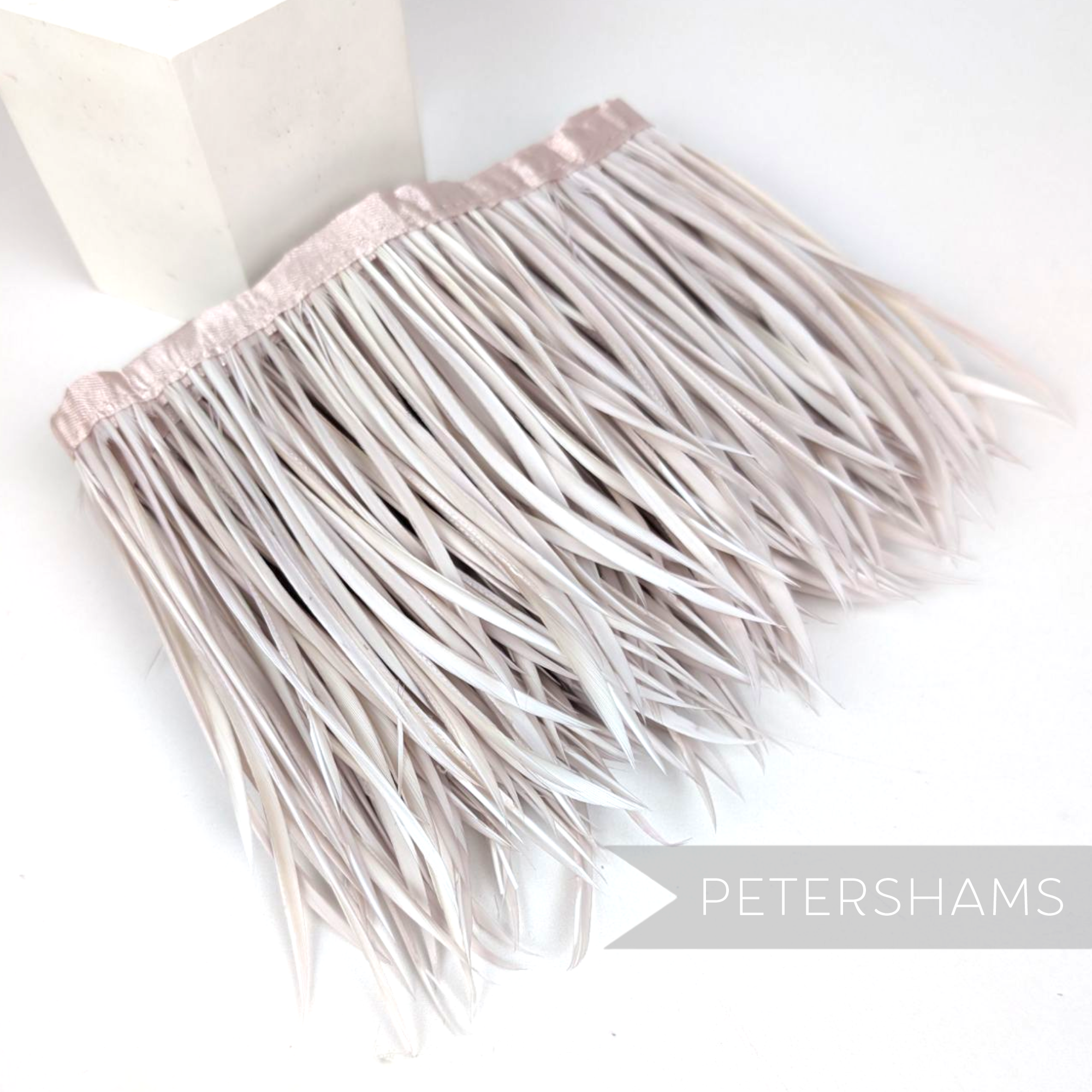 Petershams Millinery Supplies goose biot feather fringe in a soft grey shade with a matching satin ribbon binding.