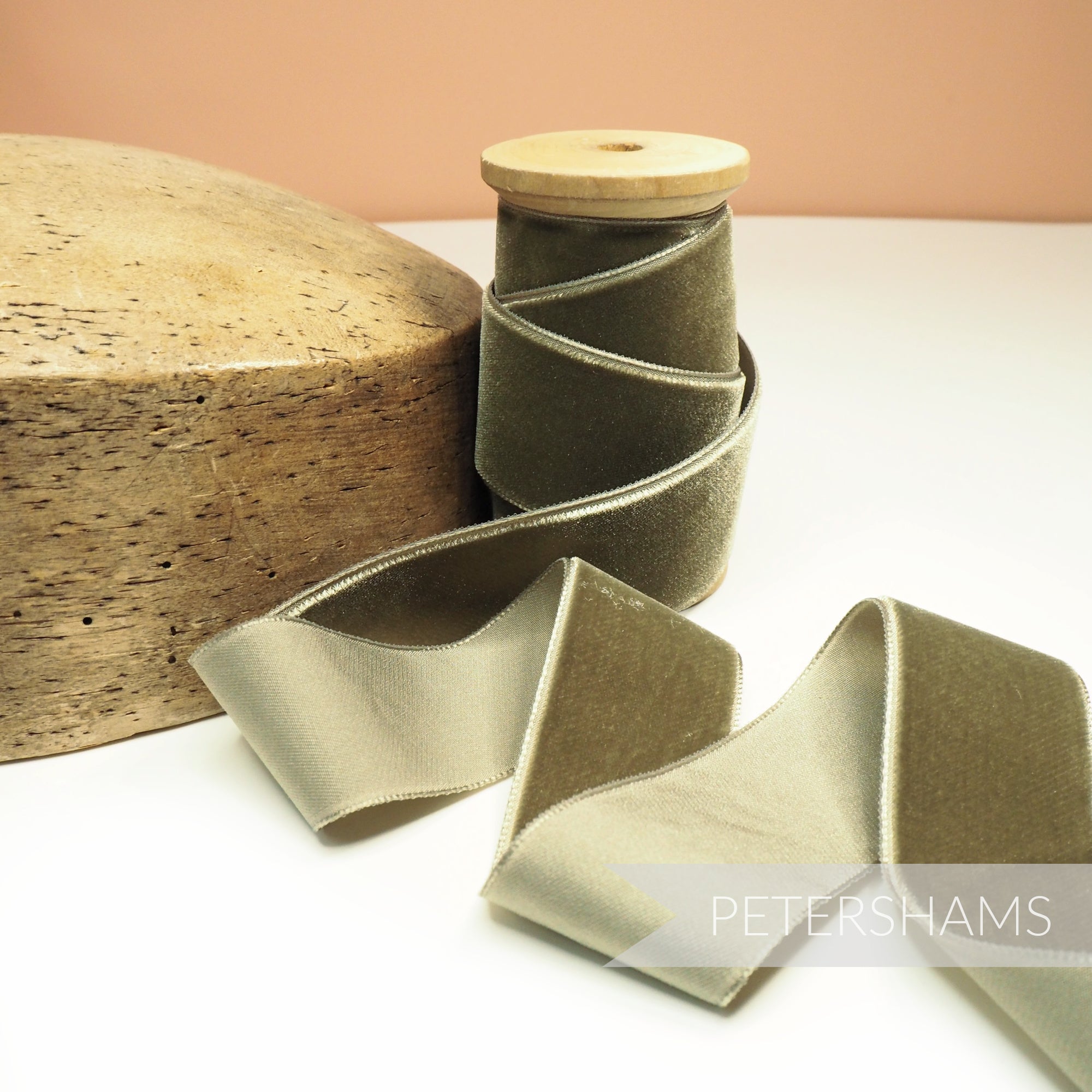 Petershams Millinery Supplies 36mm wide sage green French velvet ribbon on a wooden spool next to a millinery block