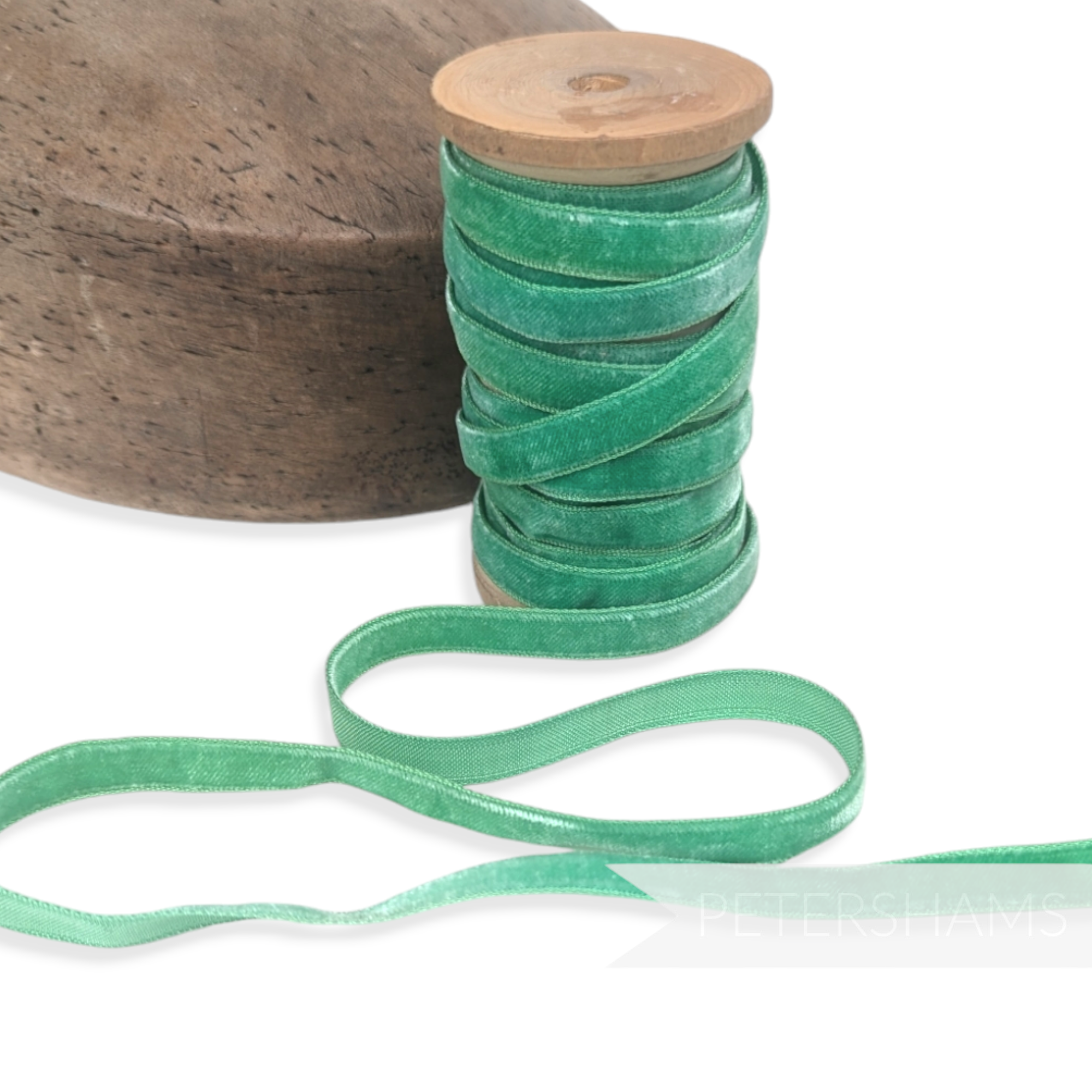 Petershams Millinery Supplies 10mm vintage green velvet ribbon on a wooden spool next to a millinery block.