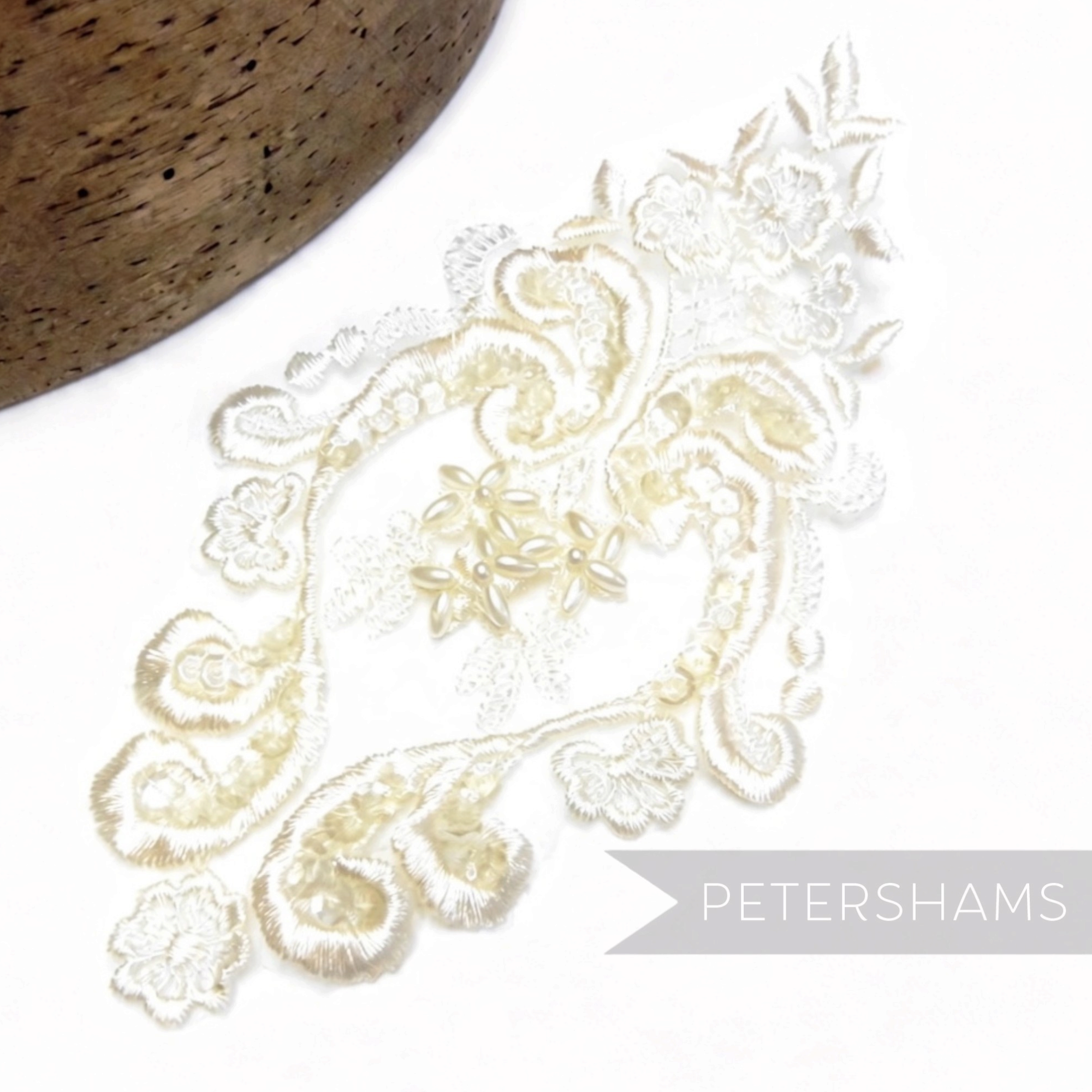 Petershams Millinery Supplies heart-shaped bridal lace motif with faux pearls and iridescent sequins on white fabric.
