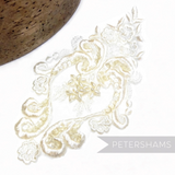 Petershams Millinery Supplies heart-shaped bridal lace motif with faux pearls and iridescent sequins on white fabric.