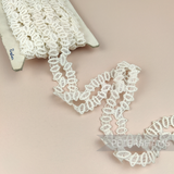 Petershams Millinery Supplies vintage 1950s ivory cotton guipure lace trim with a geometric horn scallop design.