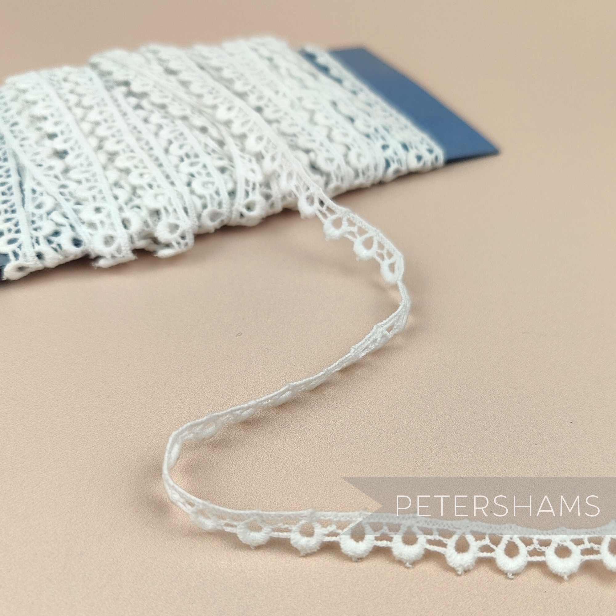 Petershams Millinery Supplies 9mm ivory cotton guipure lace trim with a vintage peephole scallop pattern on a card.