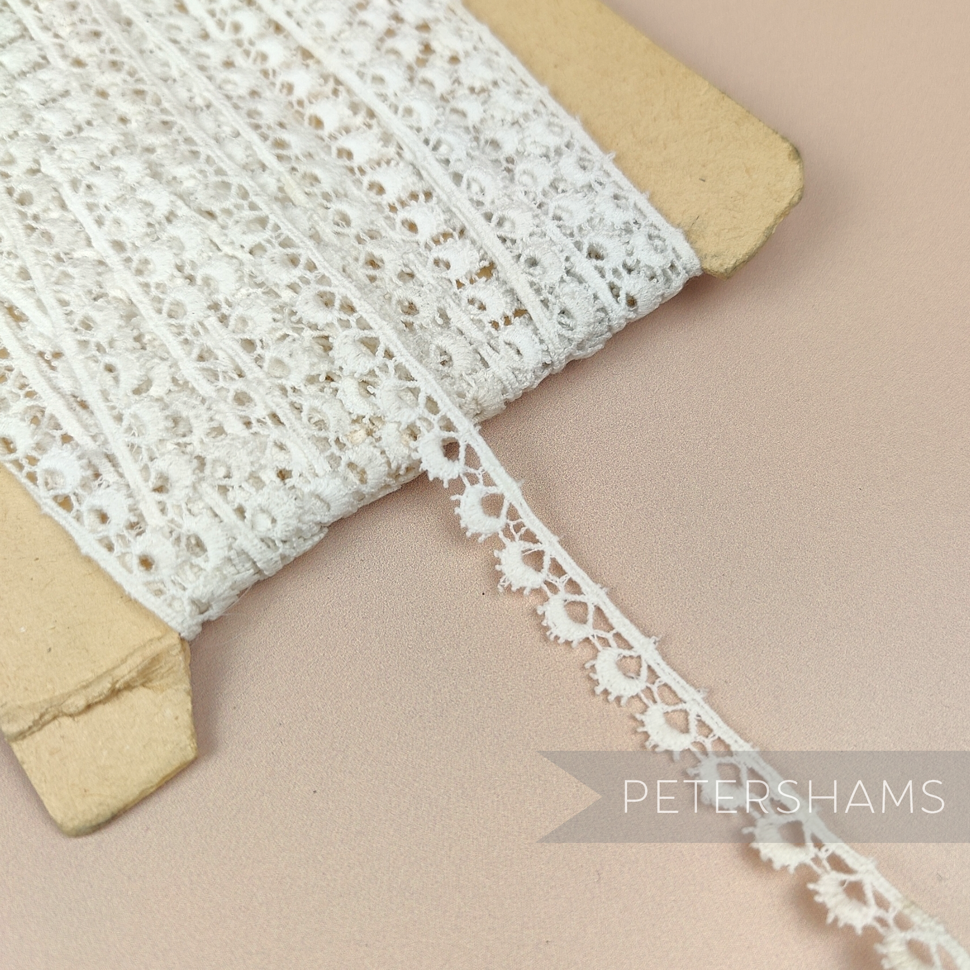 Petershams Millinery Supplies 10mm ivory cotton guipure lace trim with vintage eyelash peephole pattern on a spool.