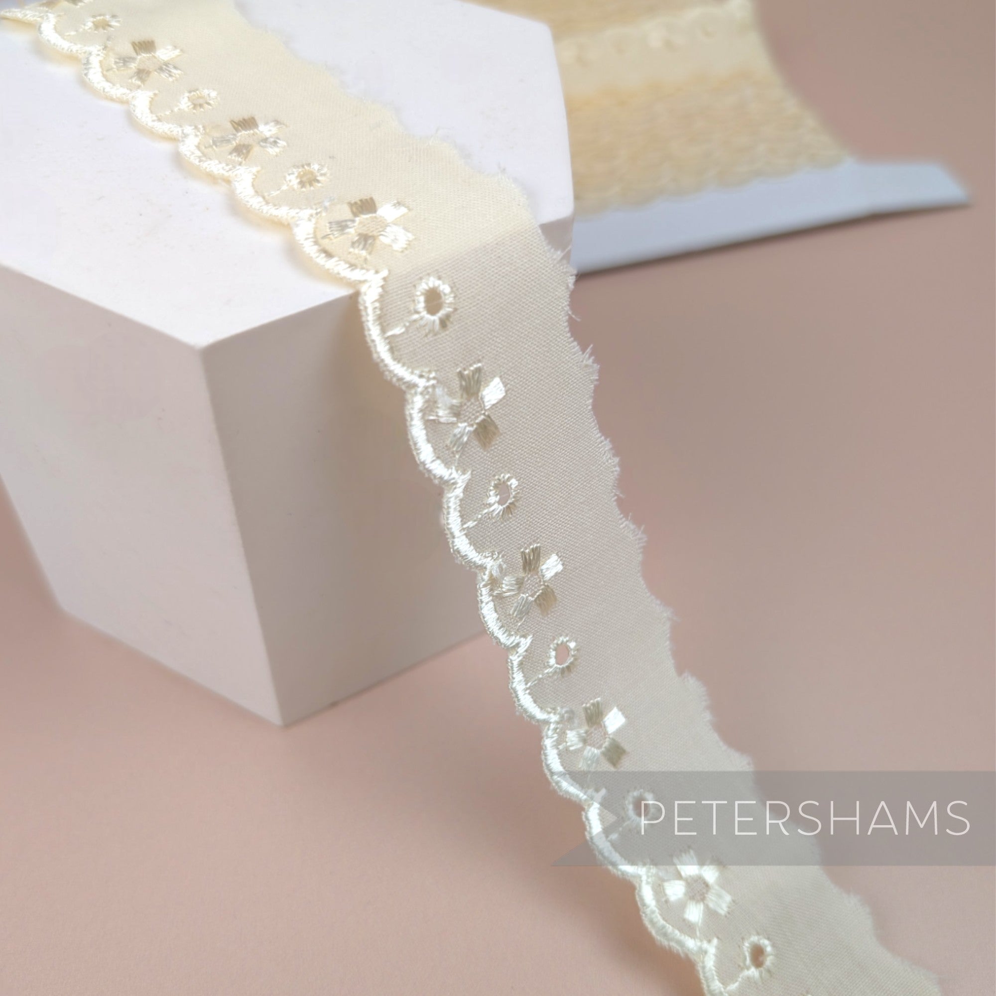 Petershams Millinery Supplies 25mm ivory broderie anglaise lace trim with floral cut-outs and a scalloped edge.