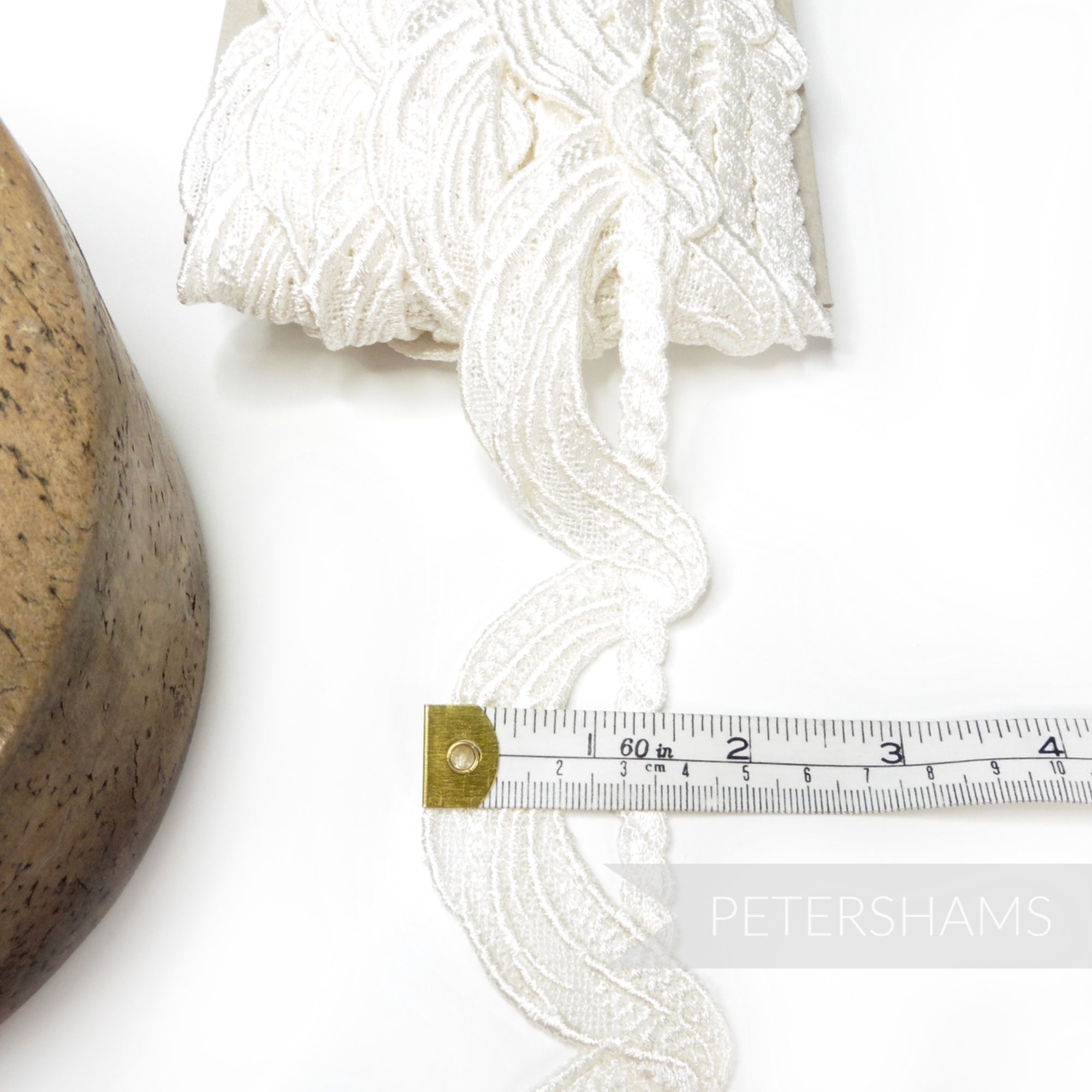 Petershams Millinery Supplies ivory 45mm guipure lace trim with a swag and twisted rope motif on a white background