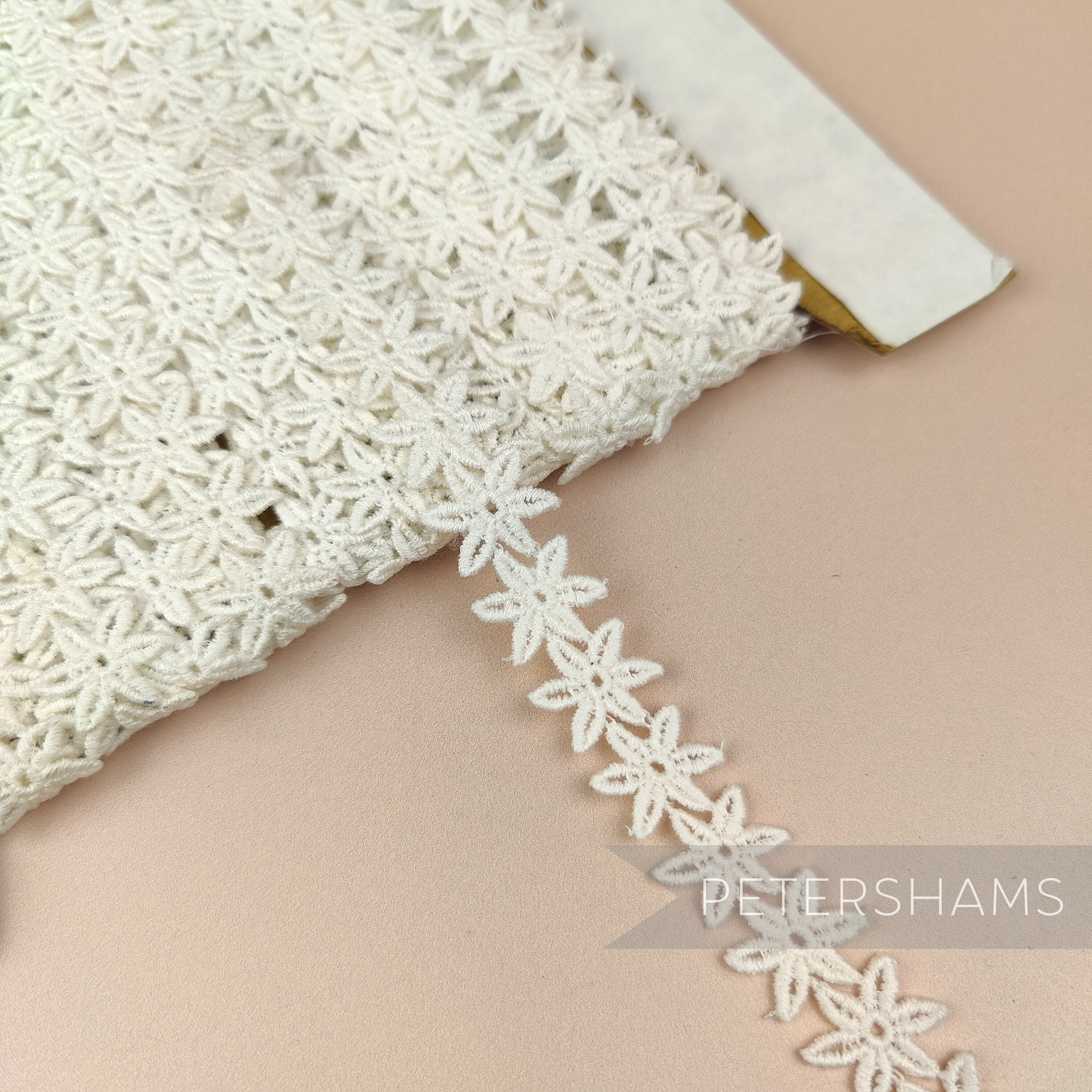 Petershams Millinery Supplies vintage 1940s ivory cotton guipure lace trim with a delicate pointed flower design.