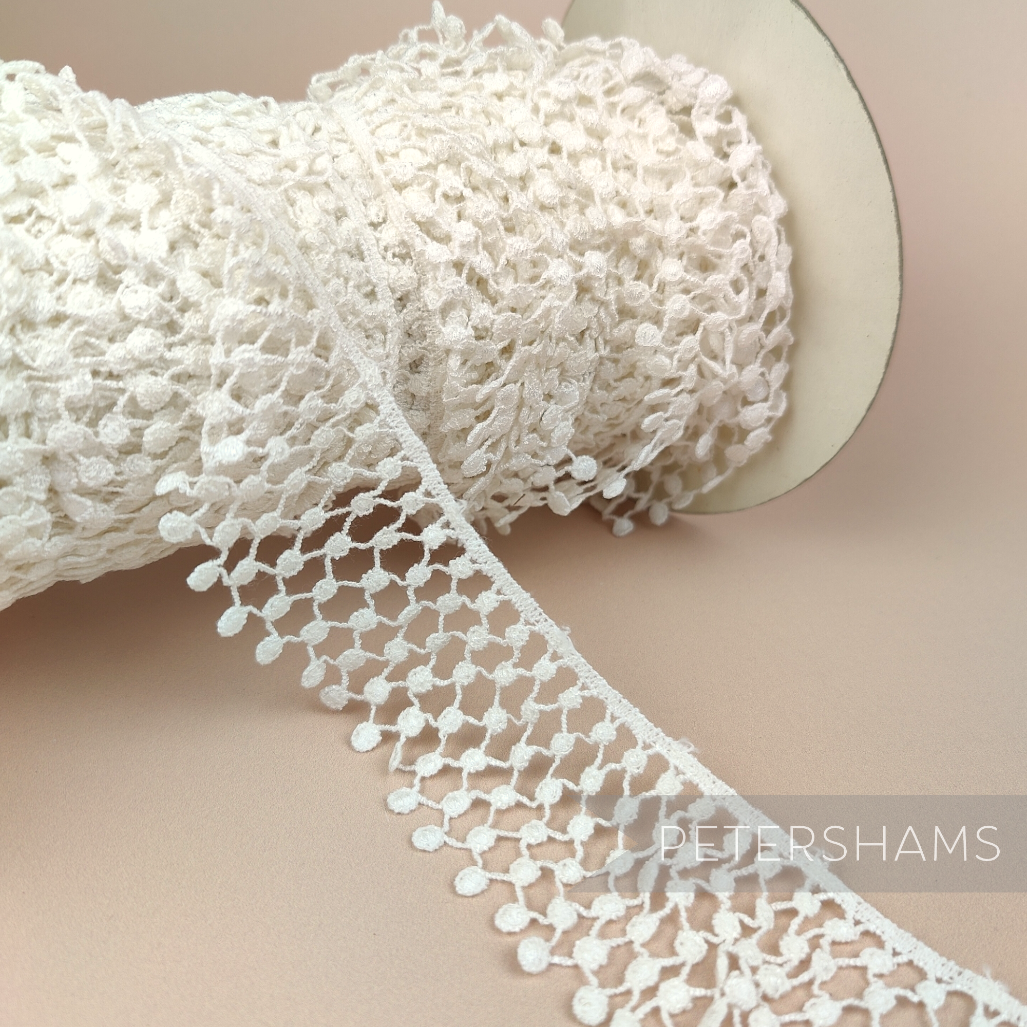 Petershams Millinery Supplies vintage ivory nylon guipure lace trim with a thatched ruffle design on a spool.