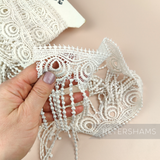 Petershams Millinery Supplies vintage 1990s ivory guipure lace trim with a peacock feather design and fringed edge.