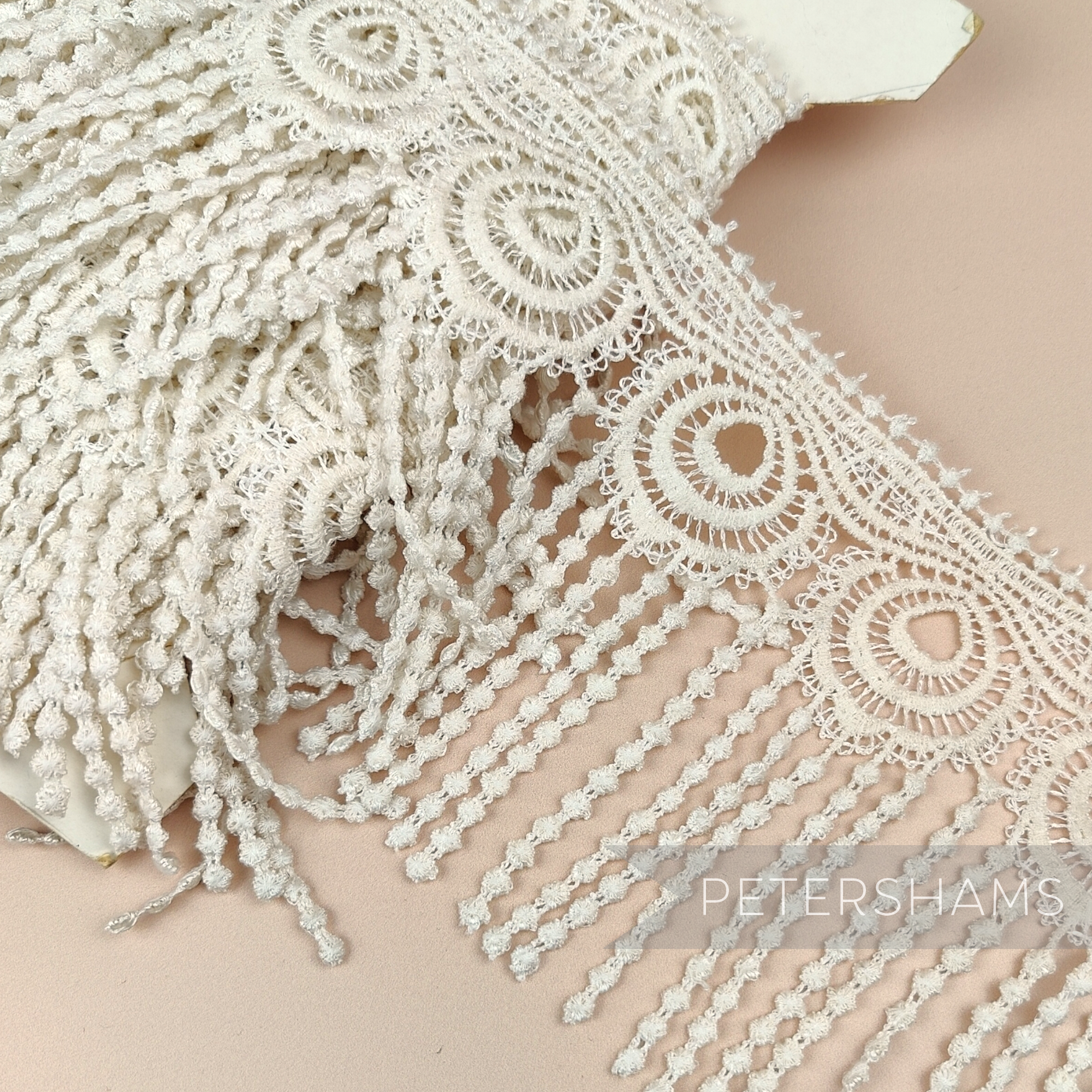 Petershams Millinery Supplies vintage 1990s ivory guipure lace trim with a wide peacock feather design and fringe.