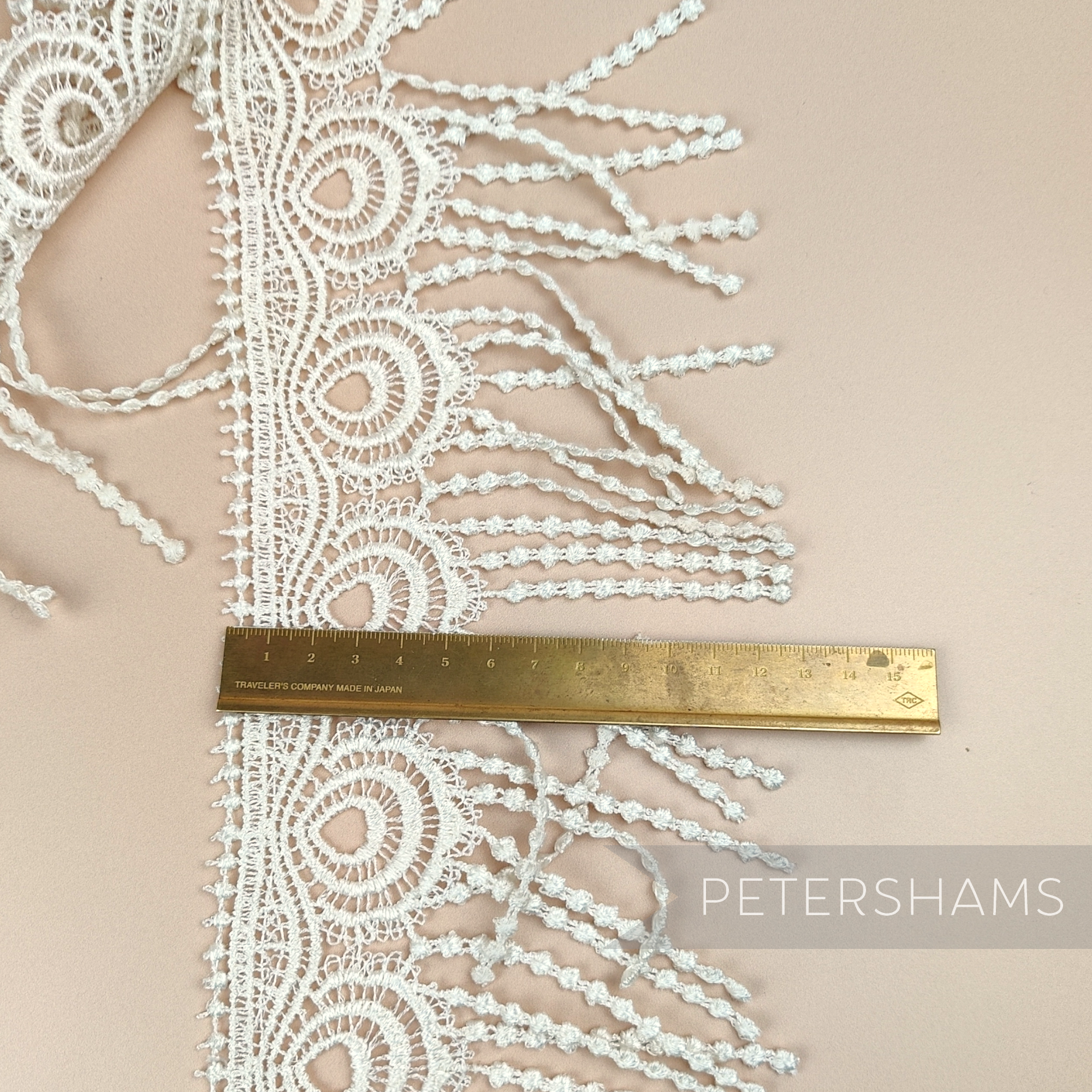 Petershams Millinery Supplies vintage 1990s ivory guipure lace trim with a peacock feather design and fringed edge.
