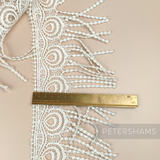 Petershams Millinery Supplies vintage 1990s ivory guipure lace trim with a peacock feather design and fringed edge.