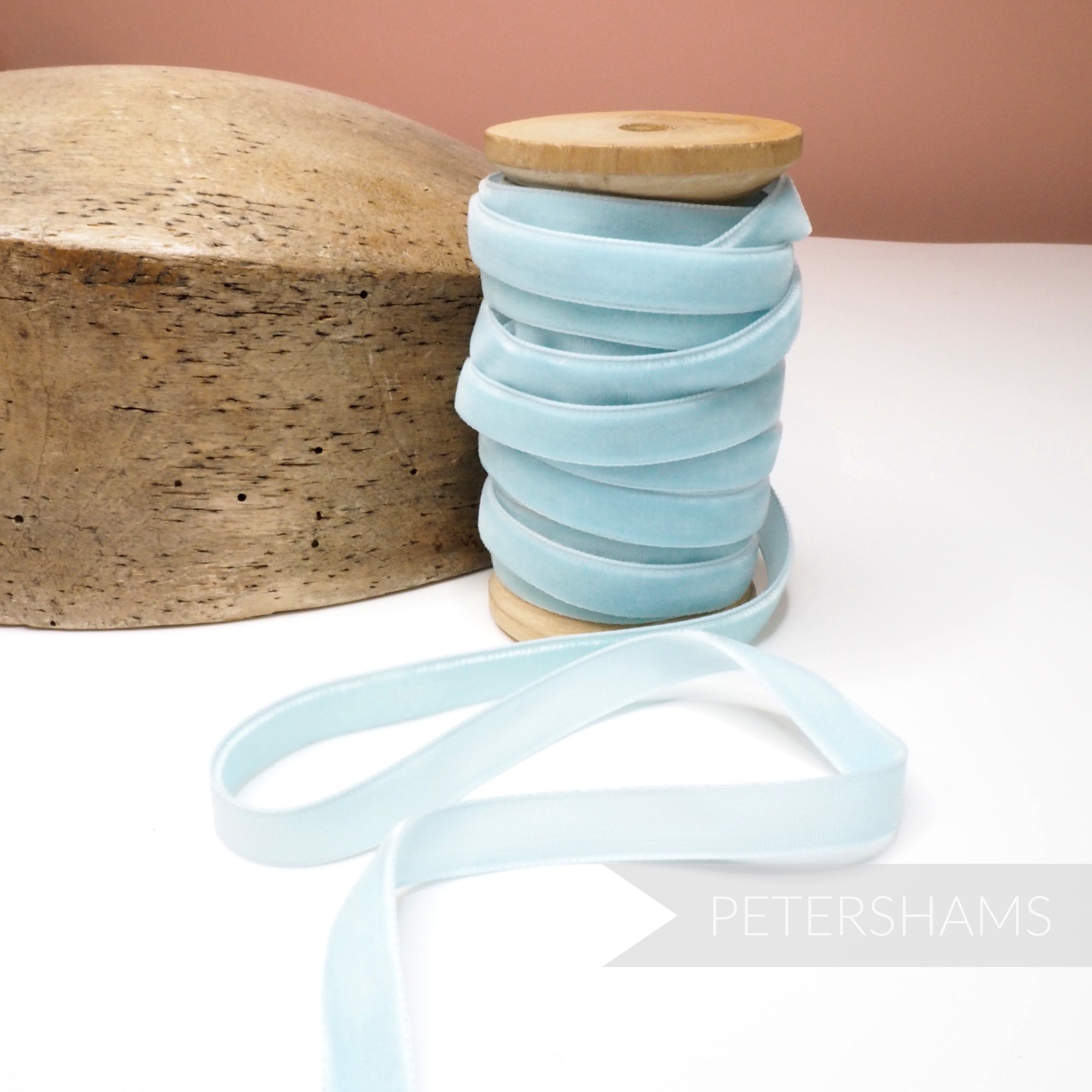Petershams Millinery Supplies 10mm light blue vintage velvet ribbon on a wooden spool next to a millinery block.