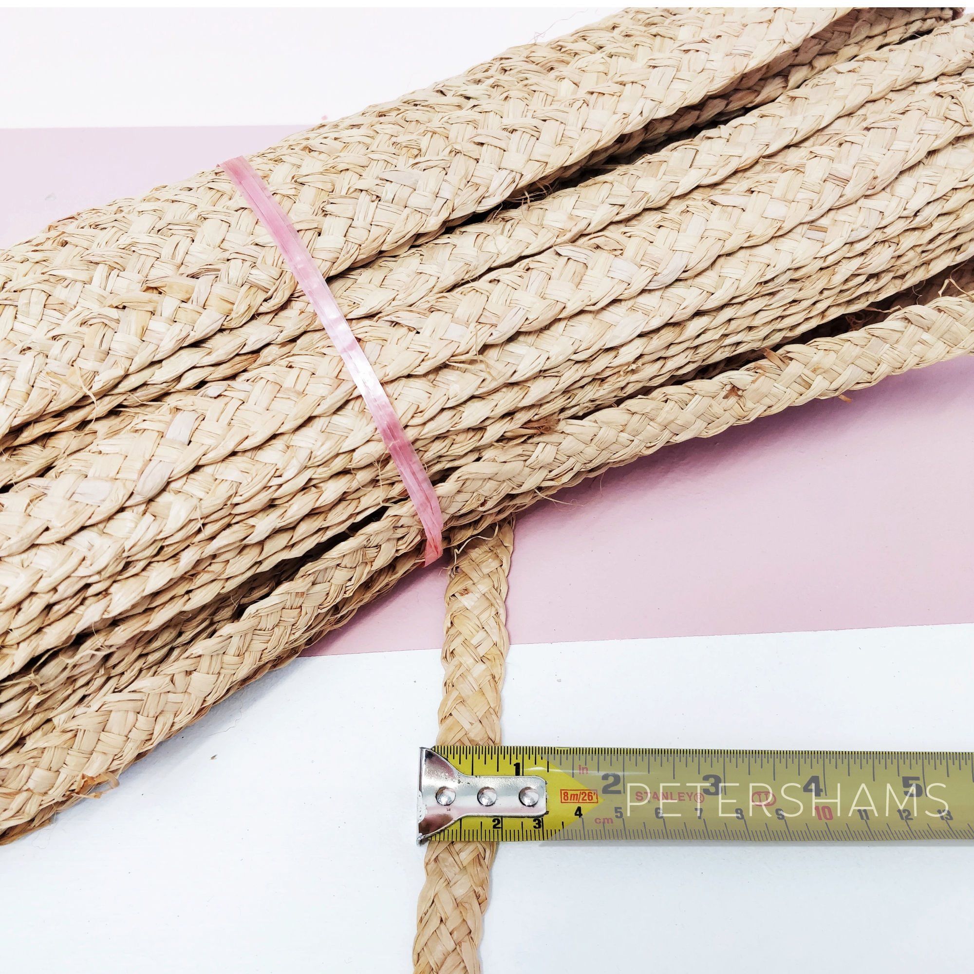 Petershams Millinery Supplies 20mm wide natural raffia braid for hat making, shown with a measuring tape.
