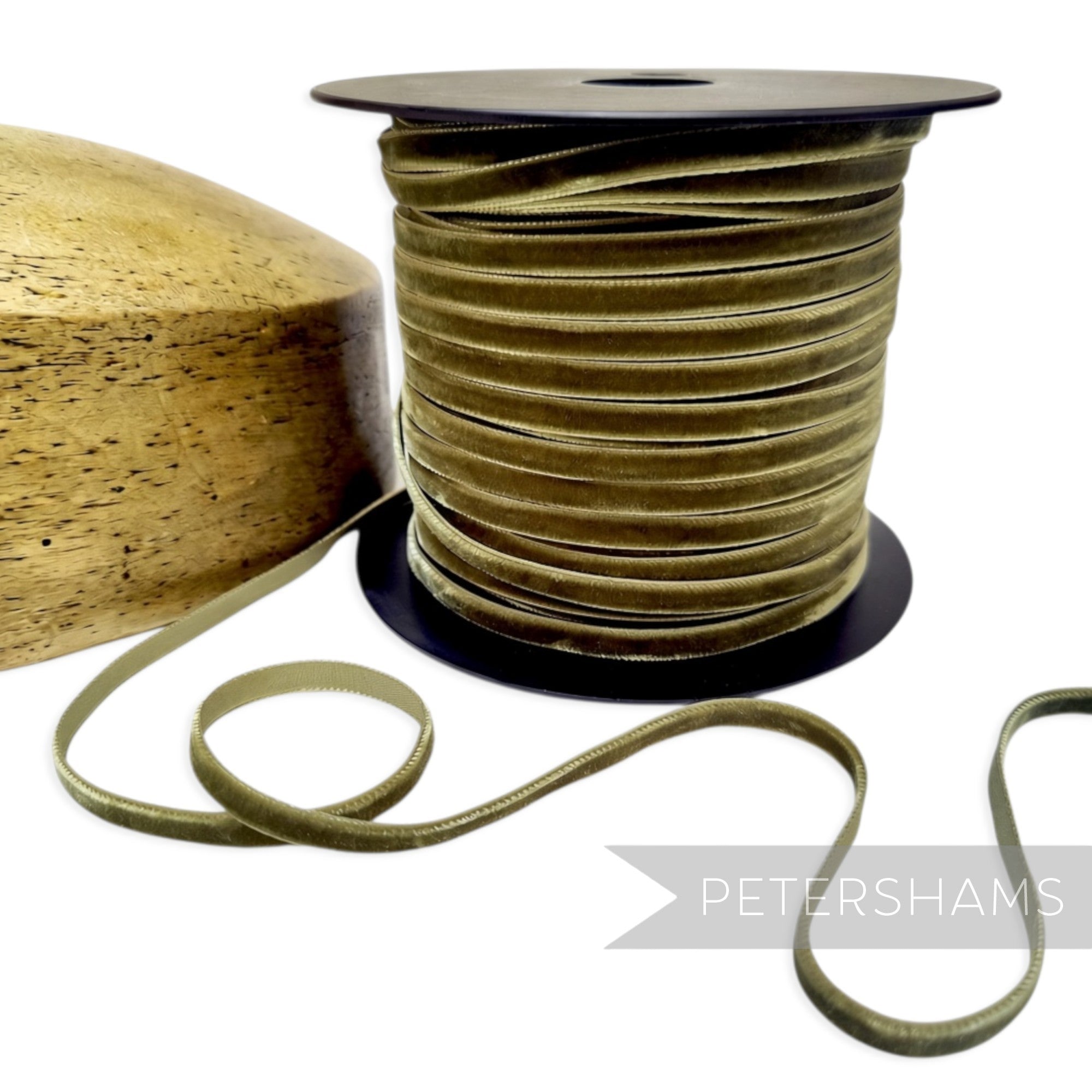 Petershams Millinery Supplies 7mm sage green French velvet ribbon on a spool next to a wooden hat block