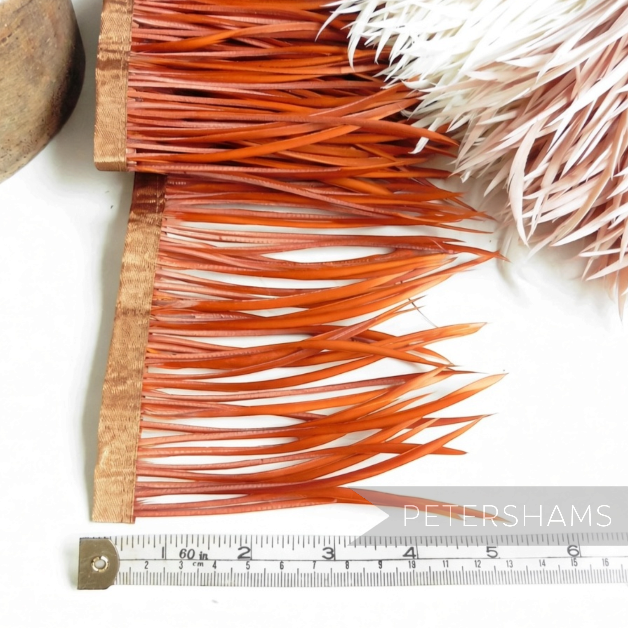 Petershams Millinery Supplies orange goose biot feather fringe on a satin ribbon binding with a measuring tape