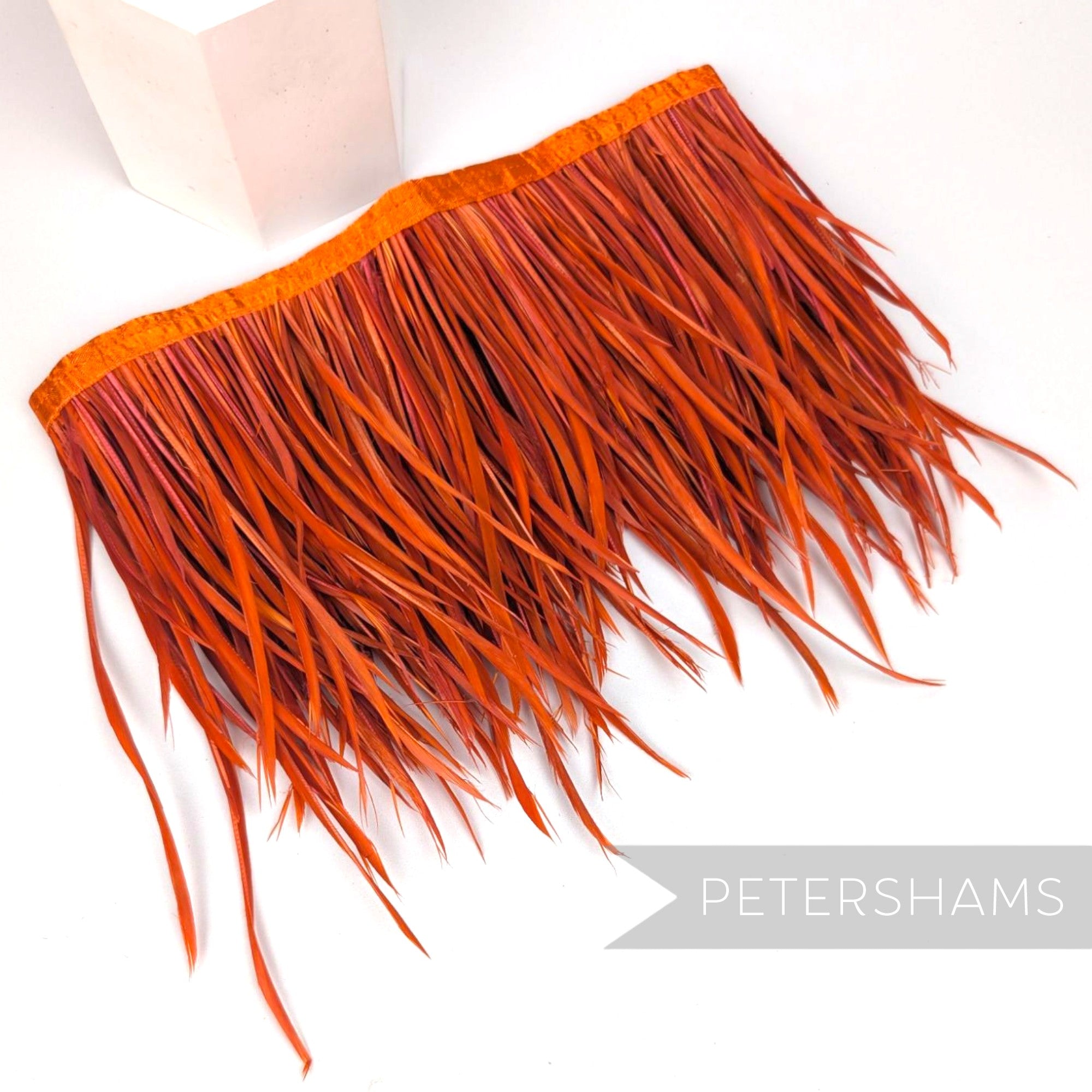 Petershams Millinery Supplies extra long burnt orange goose biot feather fringe on a stitched satin ribbon binding
