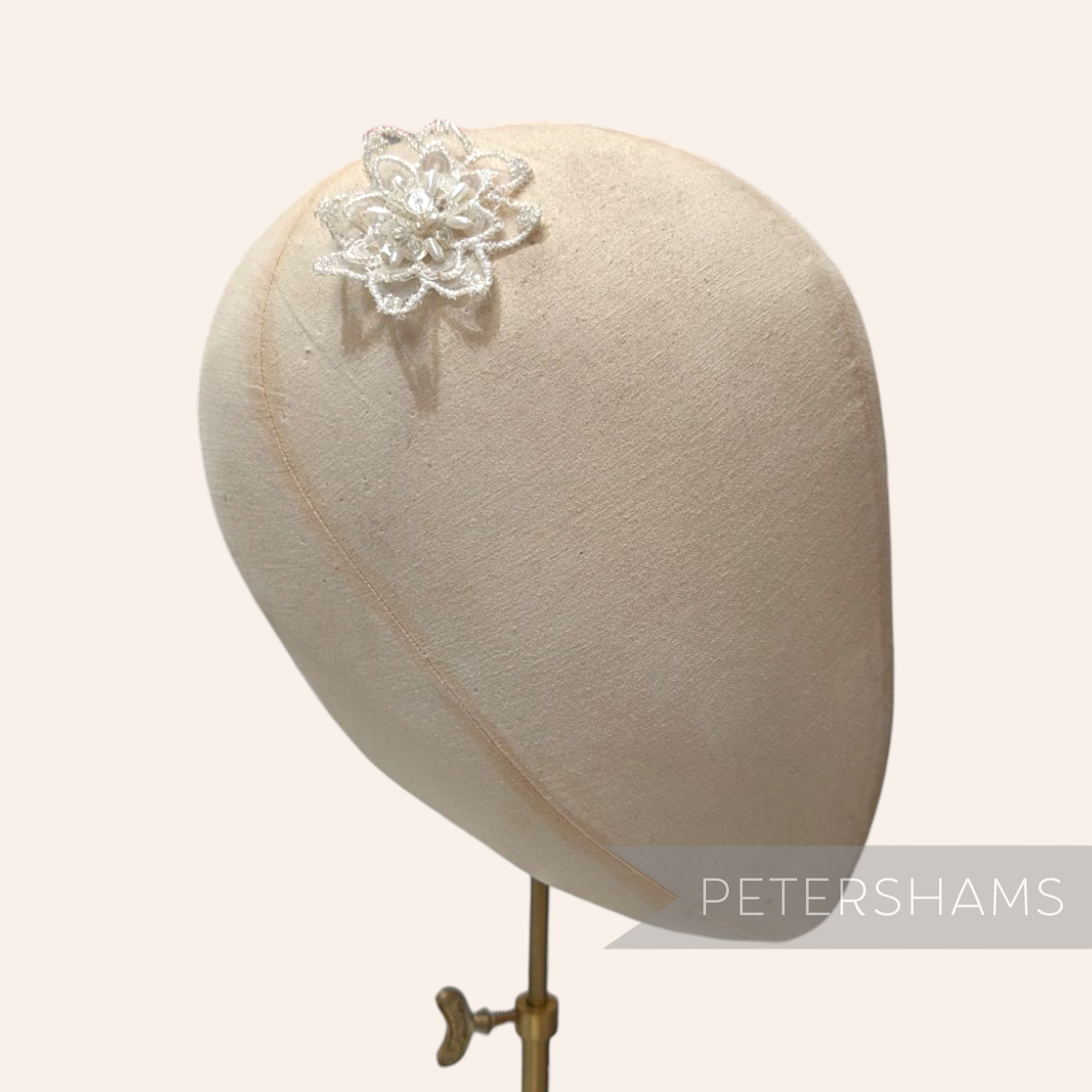 Petershams Millinery Supplies white organza flower motif with beads and sequins on a millinery head block