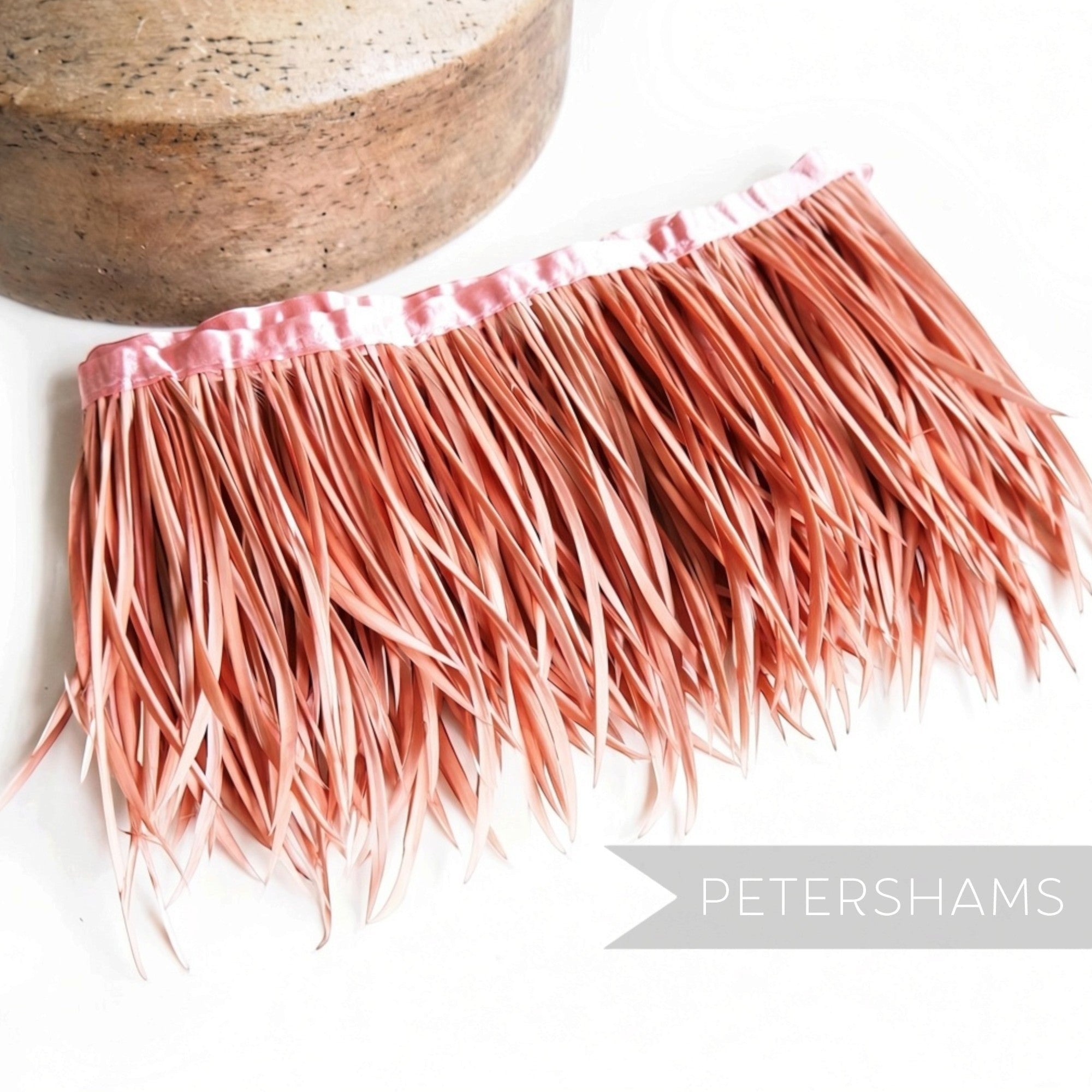 Petershams Millinery Supplies dusty pink goose biot feather fringe with satin ribbon binding on a white background.