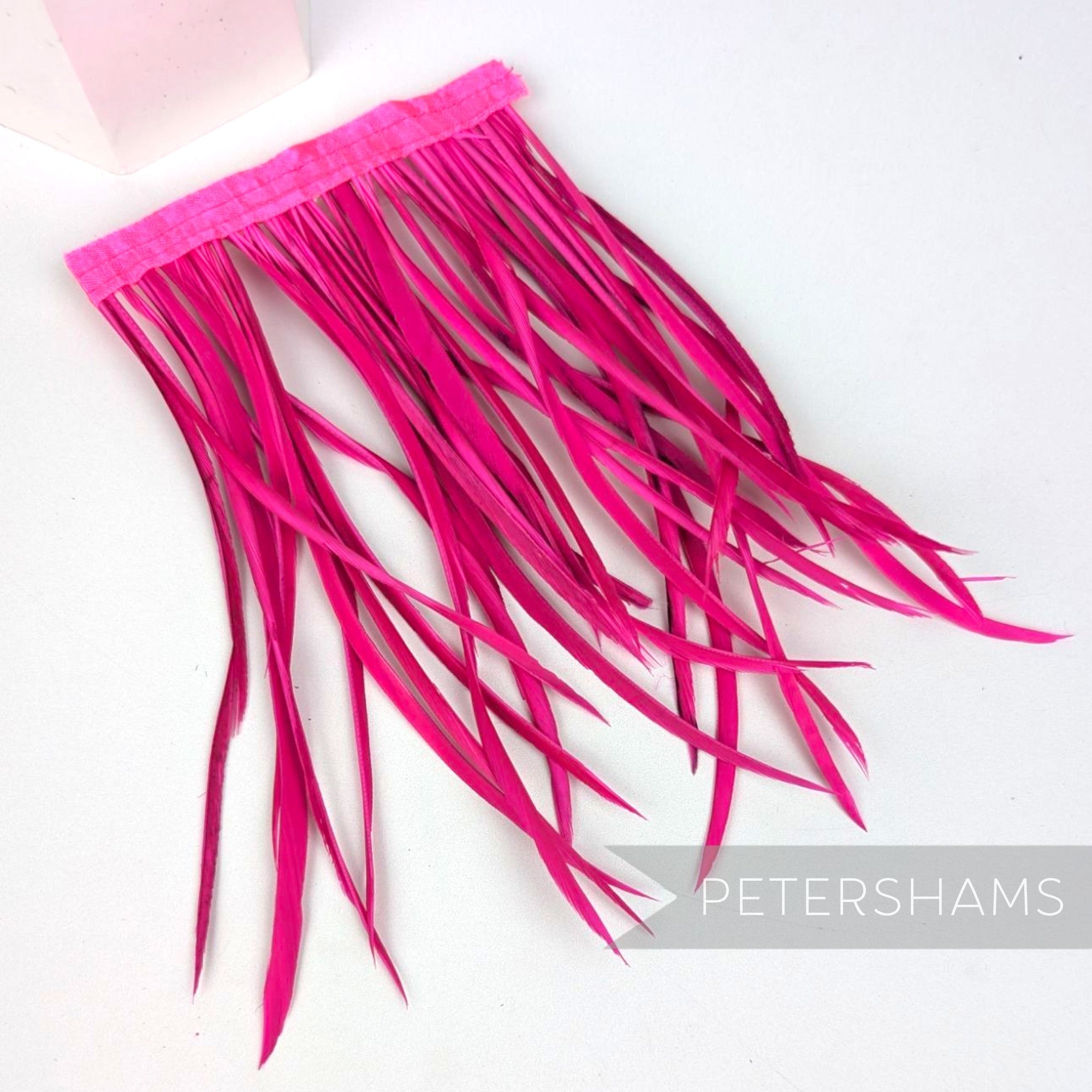 Petershams Millinery Supplies extra long neon pink goose biot feather fringe on a stitched satin ribbon binding.