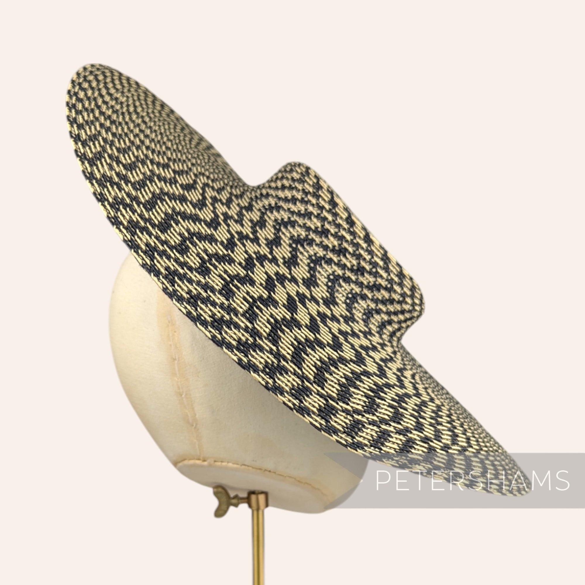 Petershams Millinery Supplies polybraid cartwheel fascinator hat base in a black and beige geometric spiral pattern.