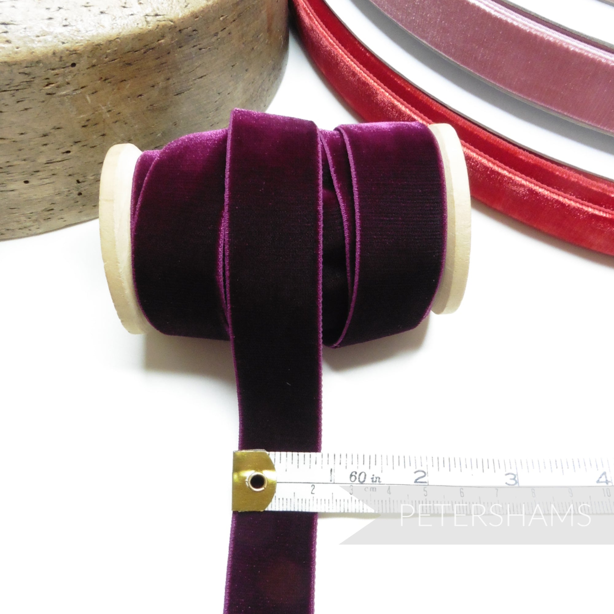 Petershams Millinery Supplies 23mm deep purple elastic velvet ribbon on a wooden spool with a measuring tape.