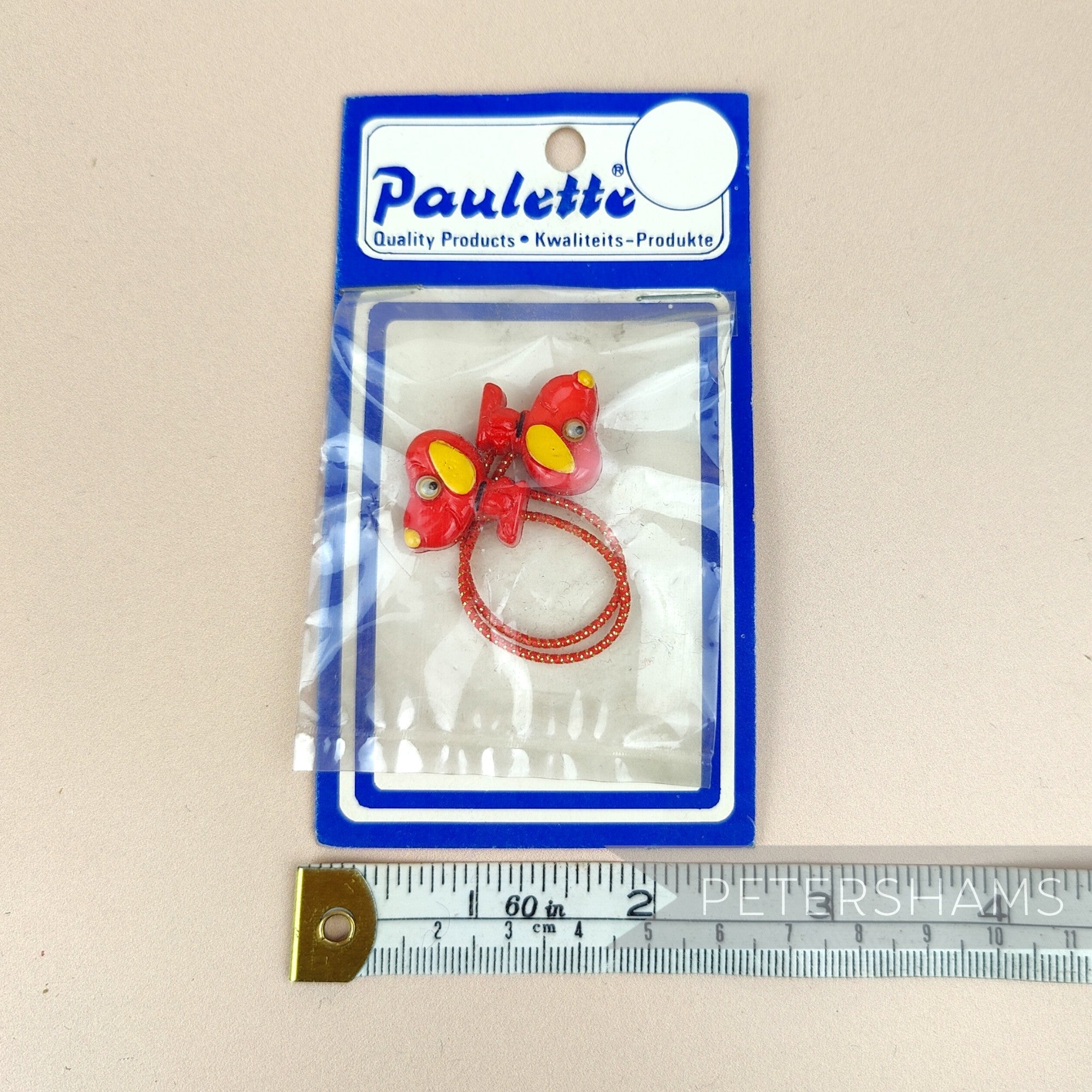 Petershams Millinery Supplies vintage red cartoon dog hair bobble in original packaging with measuring tape