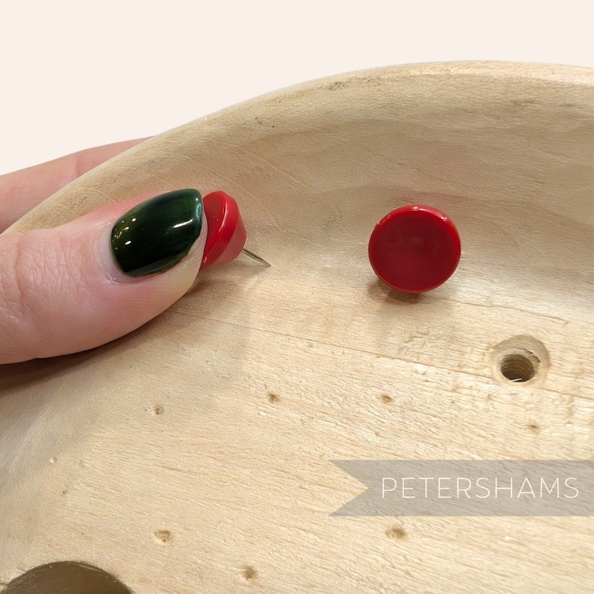 Petershams Millinery Supplies red dome-topped hat blocking pins being pressed into a wooden hat block