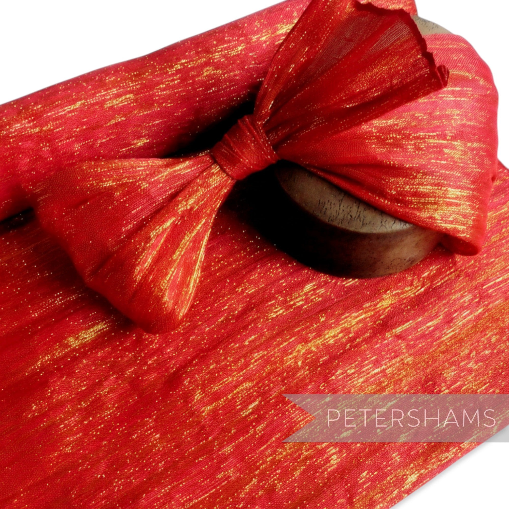 Petershams Millinery Supplies red polyester abaca fabric with lurex thread and a bow detail, ideal for headpieces.