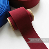 Petershams Millinery Supplies 53mm wide deep red ribbed belting ribbon on a wooden spool with blue ribbon in background