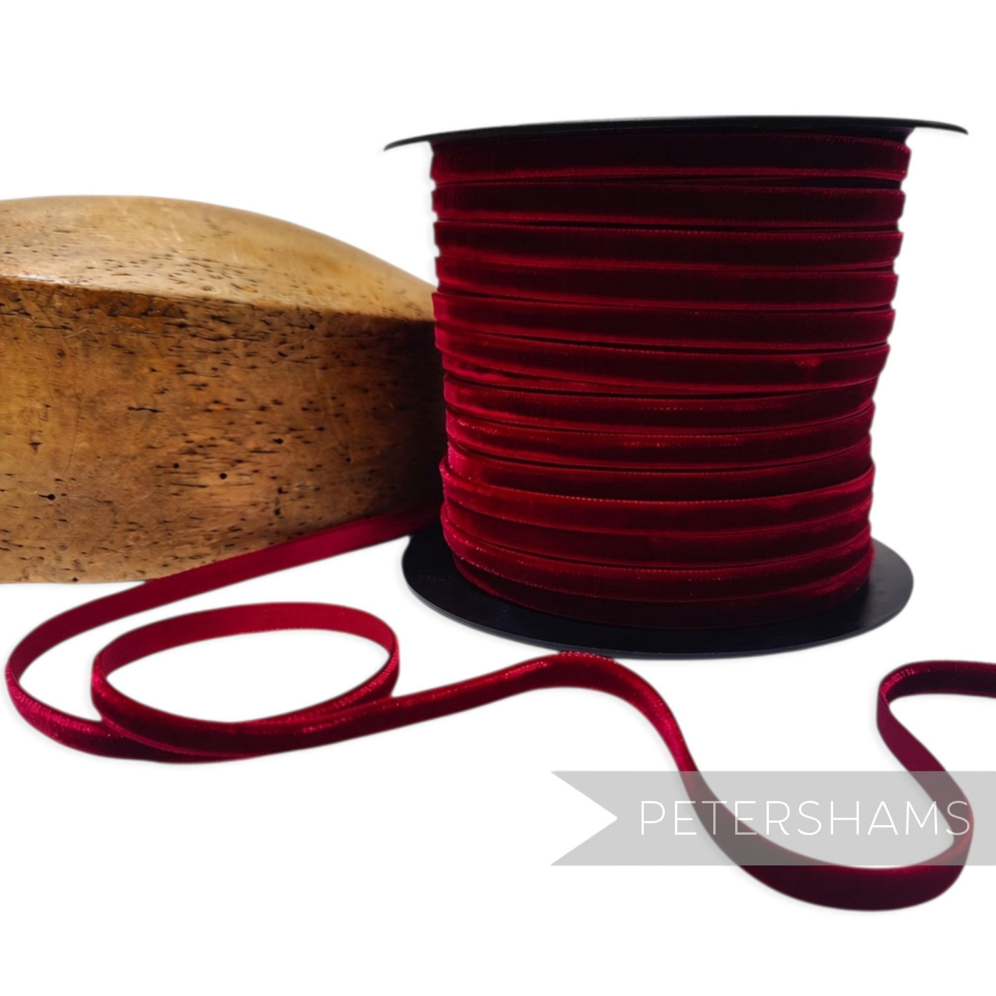 Petershams Millinery Supplies 7mm deep red French velvet ribbon on a spool next to a wooden millinery block.
