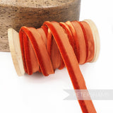 Petershams Millinery Supplies 5mm rust orange velvet insertion piping cord on a wooden spool for millinery projects.